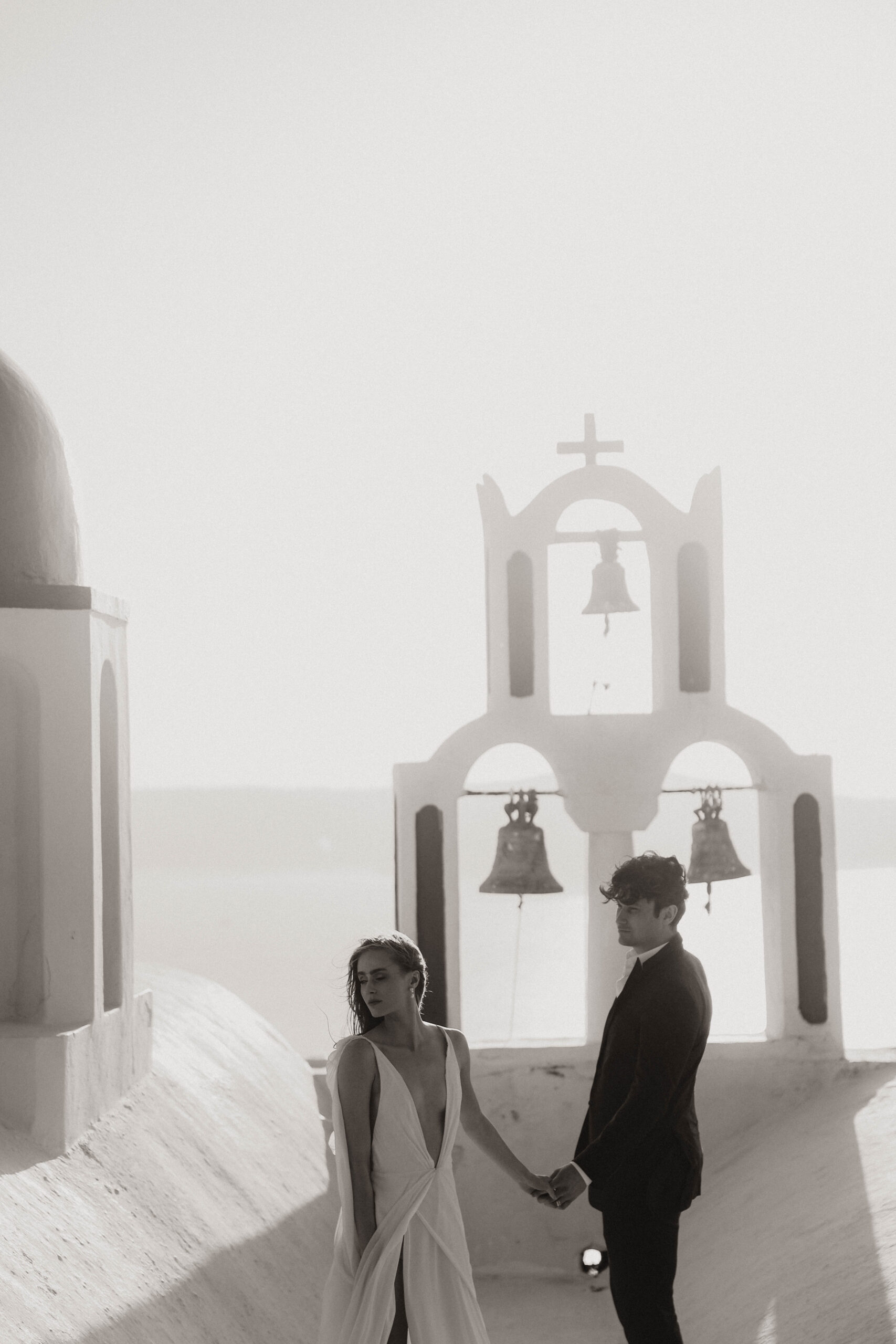 bride and groom holding hands on a white roof during their Santorini Greece elopement
