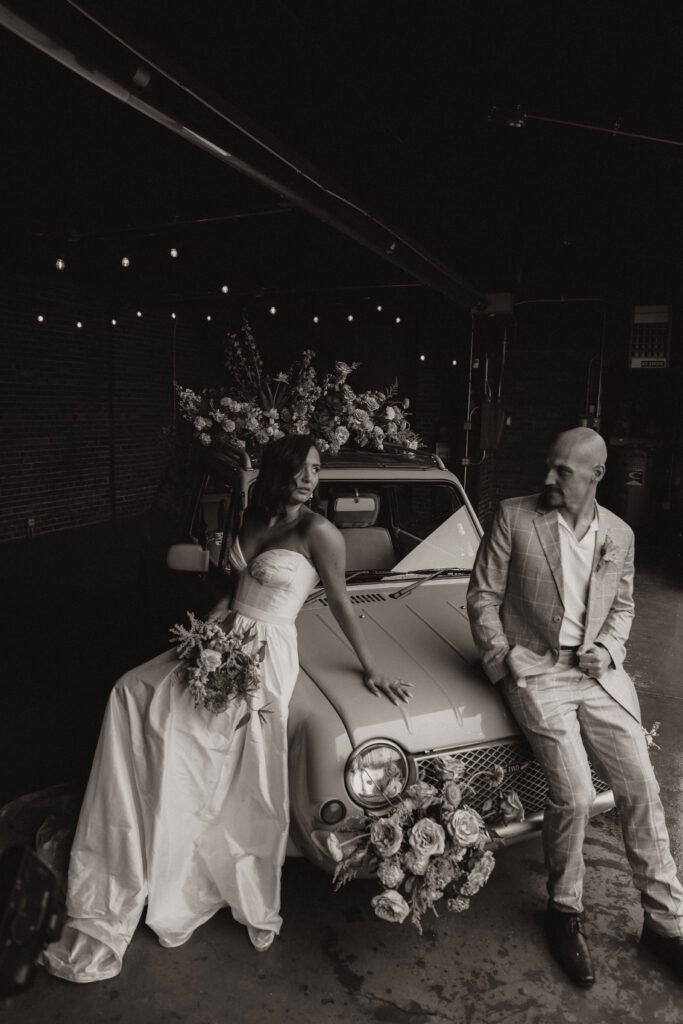 a bride and groom sitting on a car with flowers all around during a colorful spring wedding 