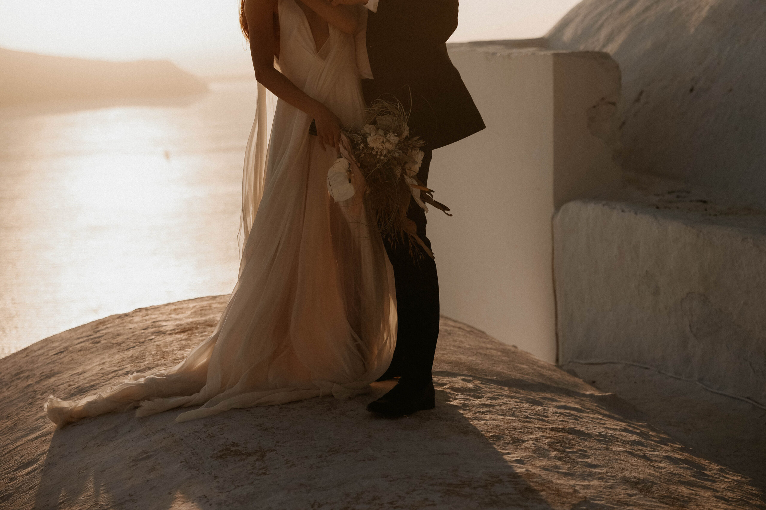 photo of bride and groom from the neck down with the sea behind them during their Santorini Greece elopement