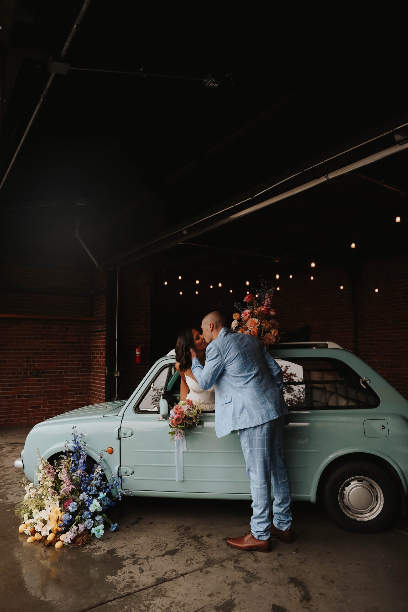 bride and groom kissing through the car window during a colorful spring wedding 