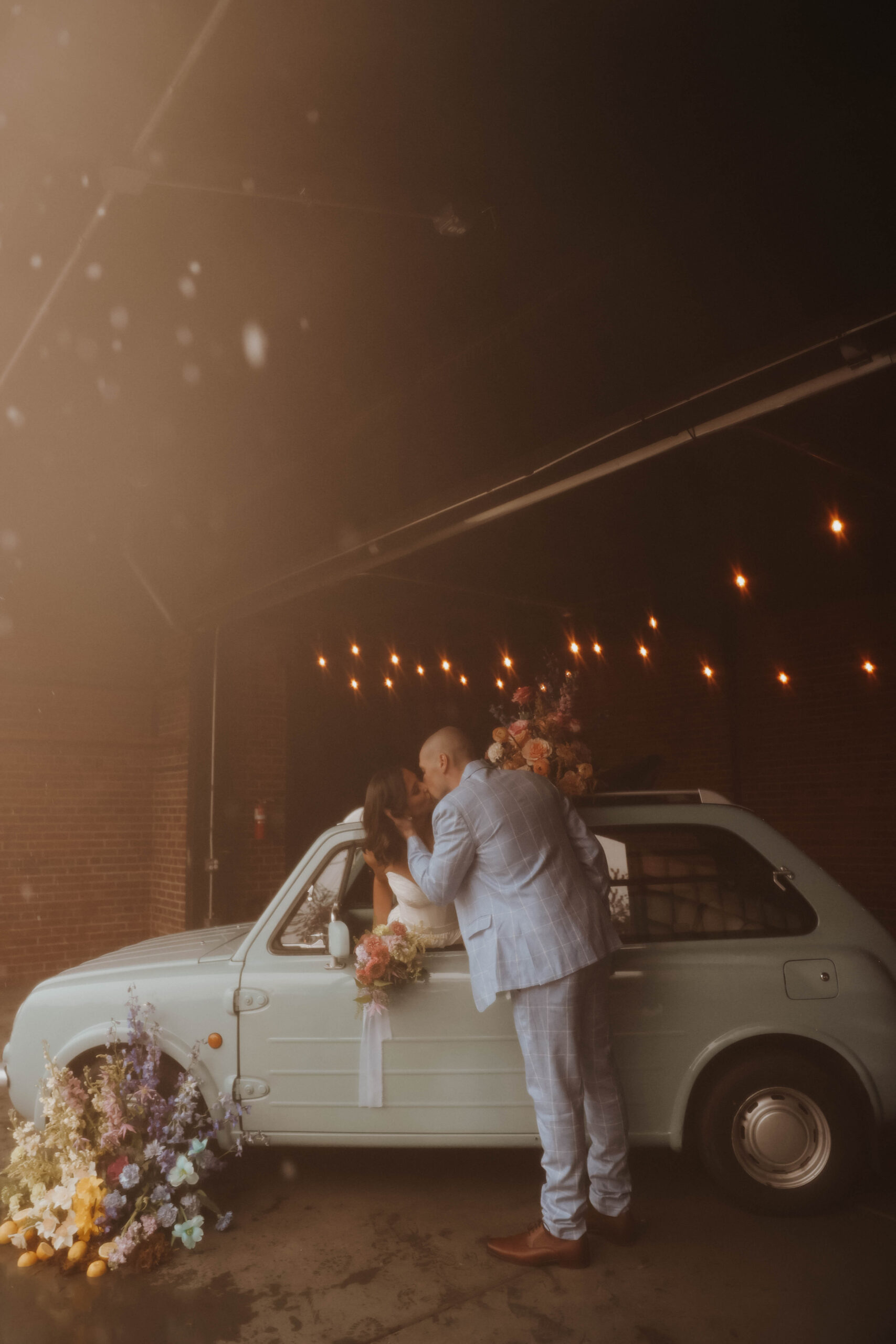 vintage looking photo of brie and groom kissing through the window of the car