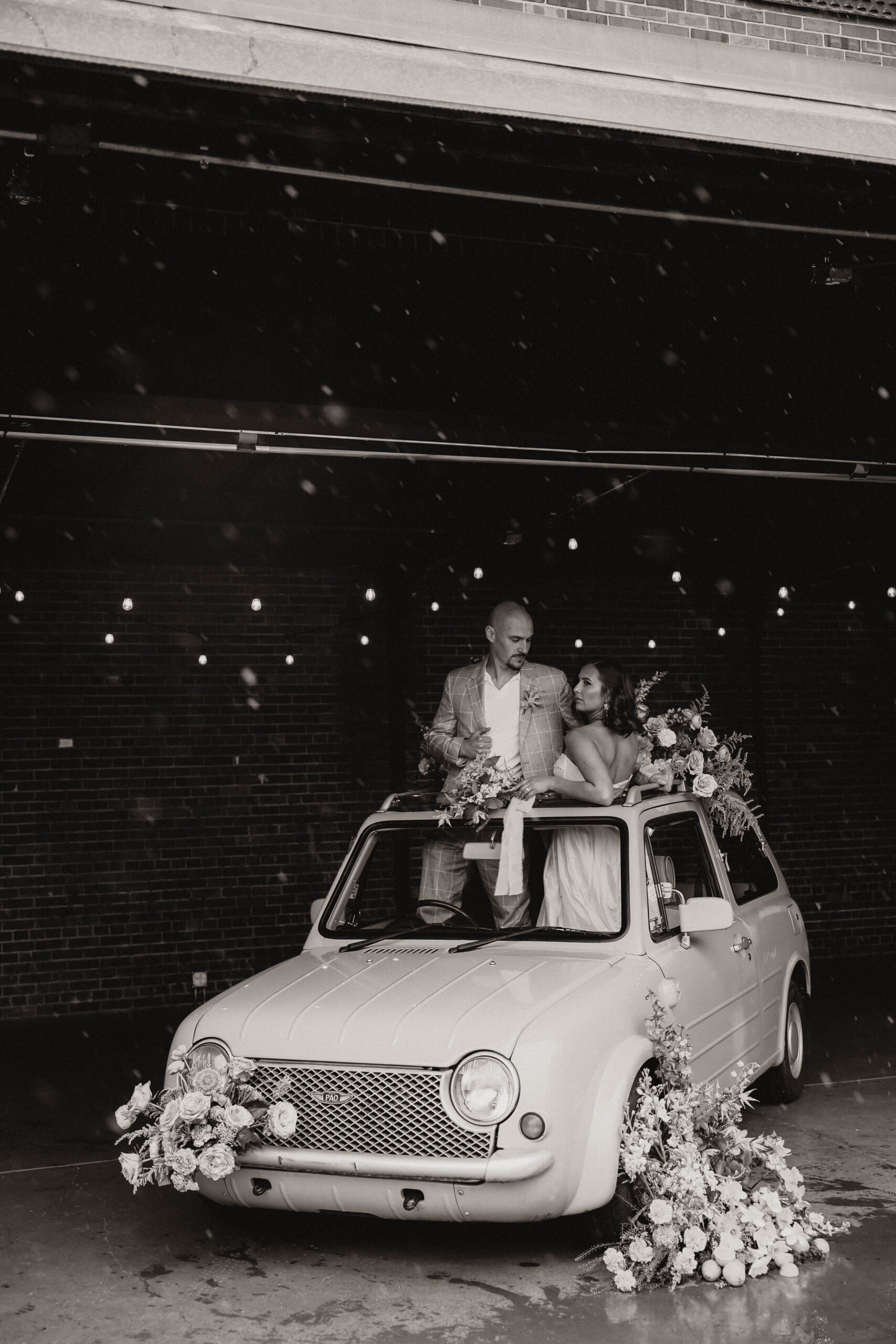 a bride and groom standing through a sun roof in a floral styled car during a colorful spring wedding 