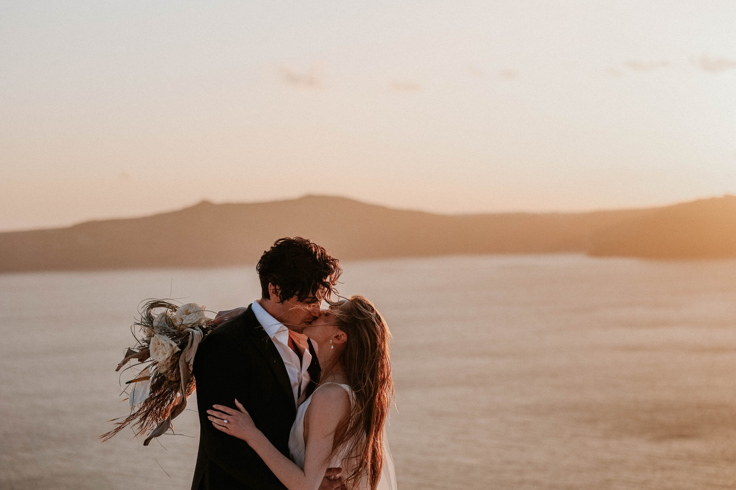 bride and groom kissing at sunset during Santorini Greece elopement