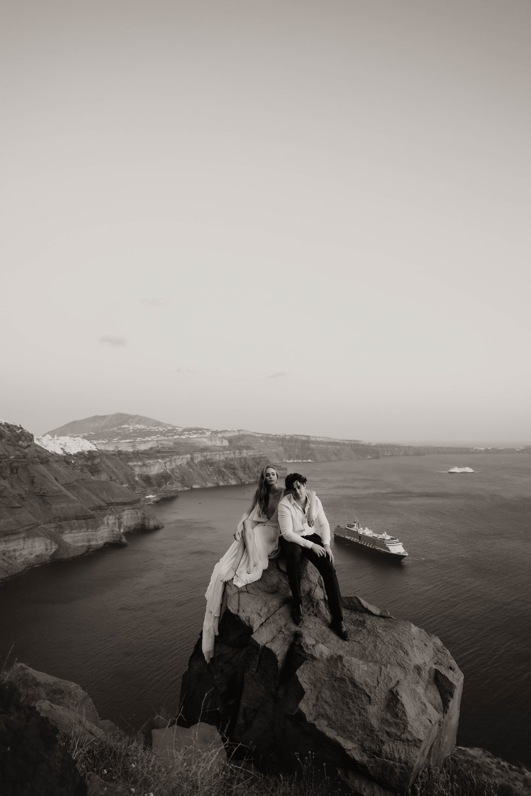 bride and groom sitting on a rock during their Santorini Greece elopement
