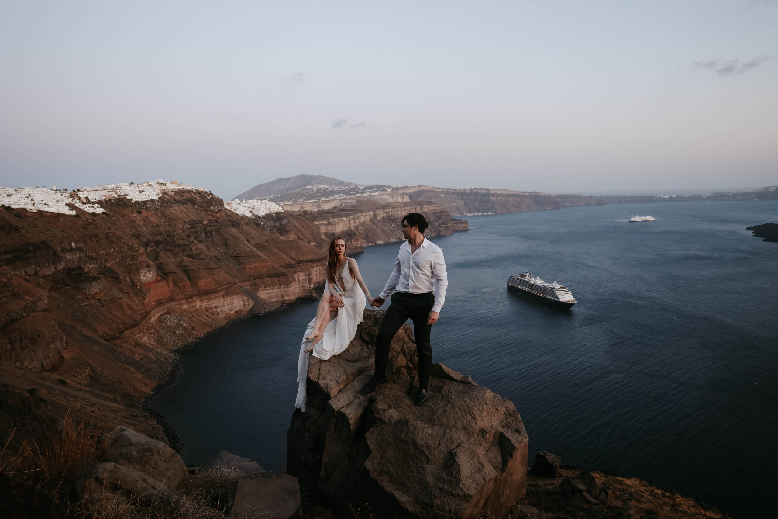 newly weds posing on a cliff at their Santorini Greece elopement