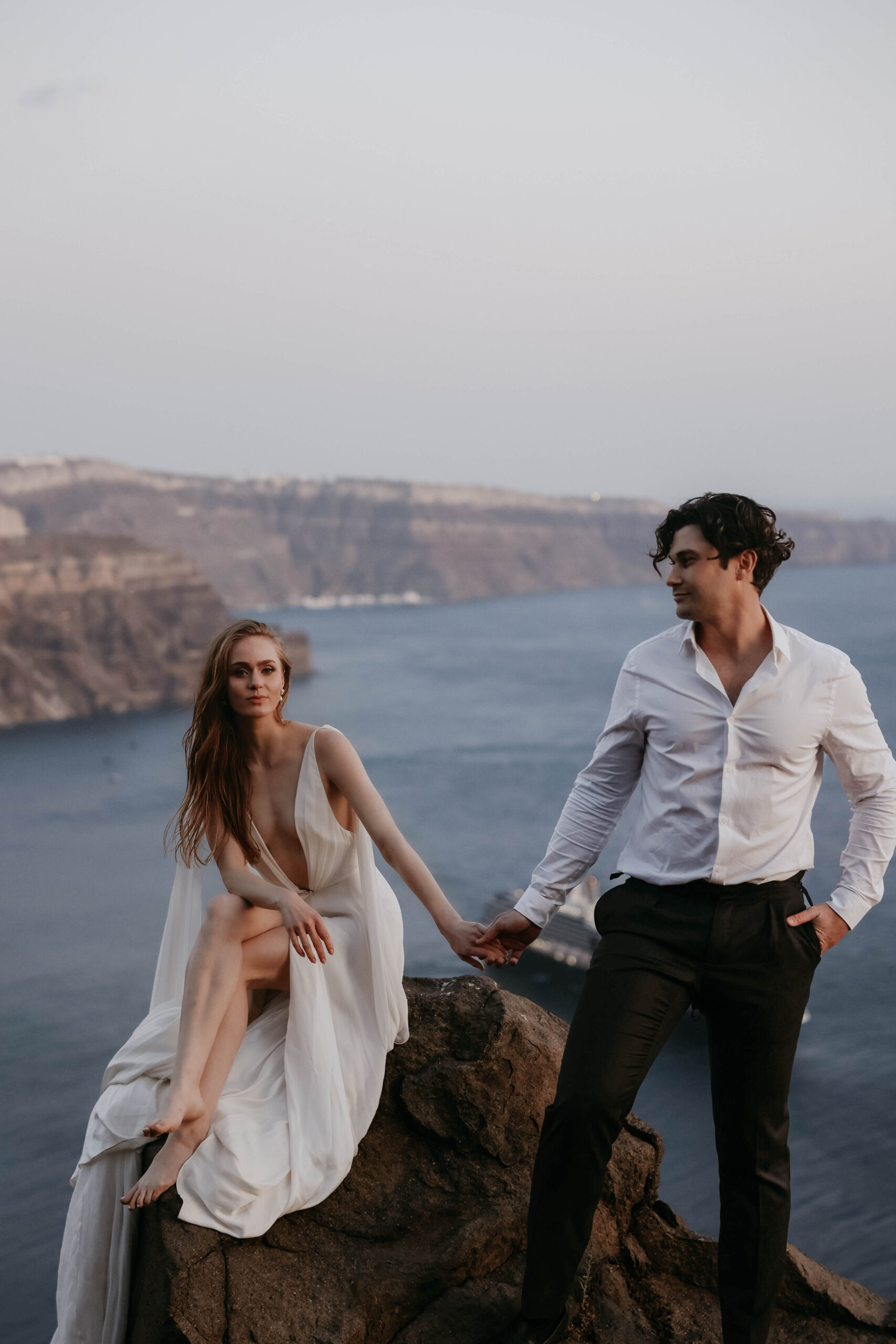 bride and groom holding hands with the ocean and cliffs behind them 