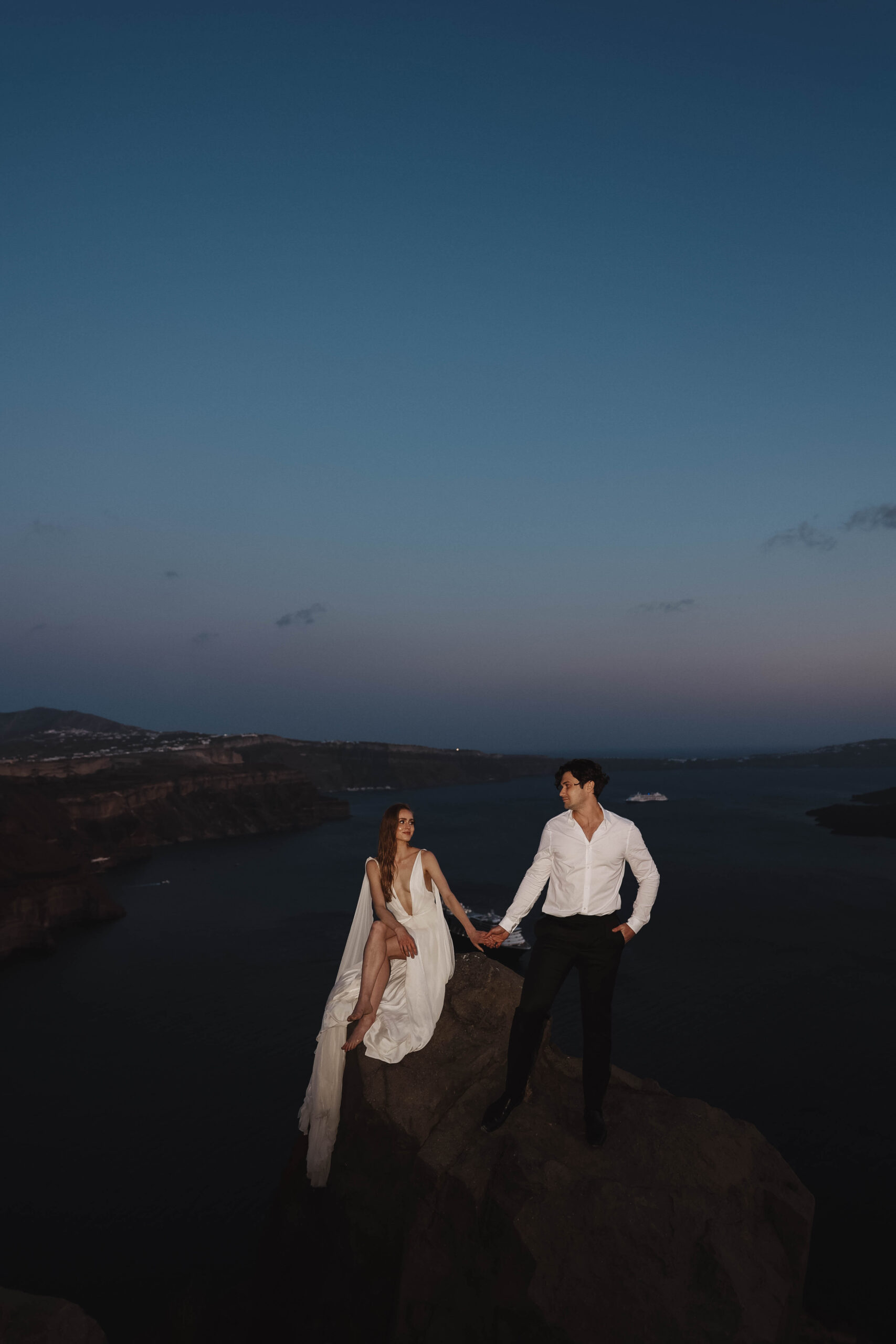 Santorini Greece elopement flash photo of bride and groom on a cliff 