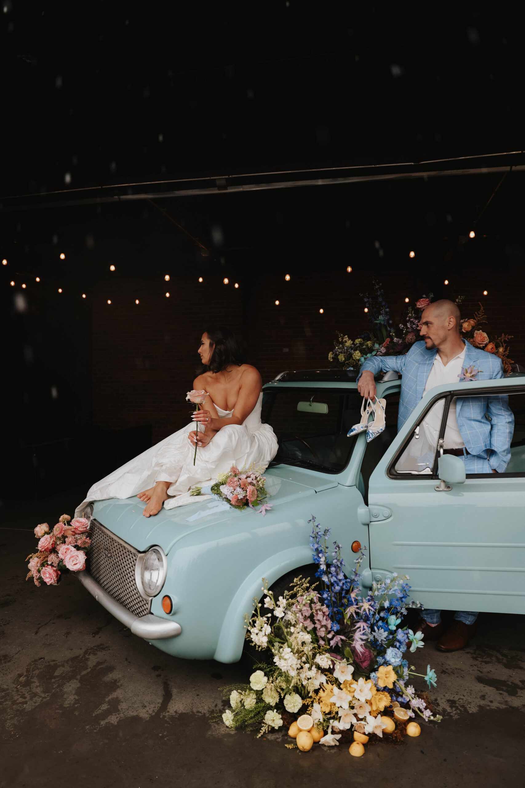 bride and groom portrait next to the car styled with wedding flowers 