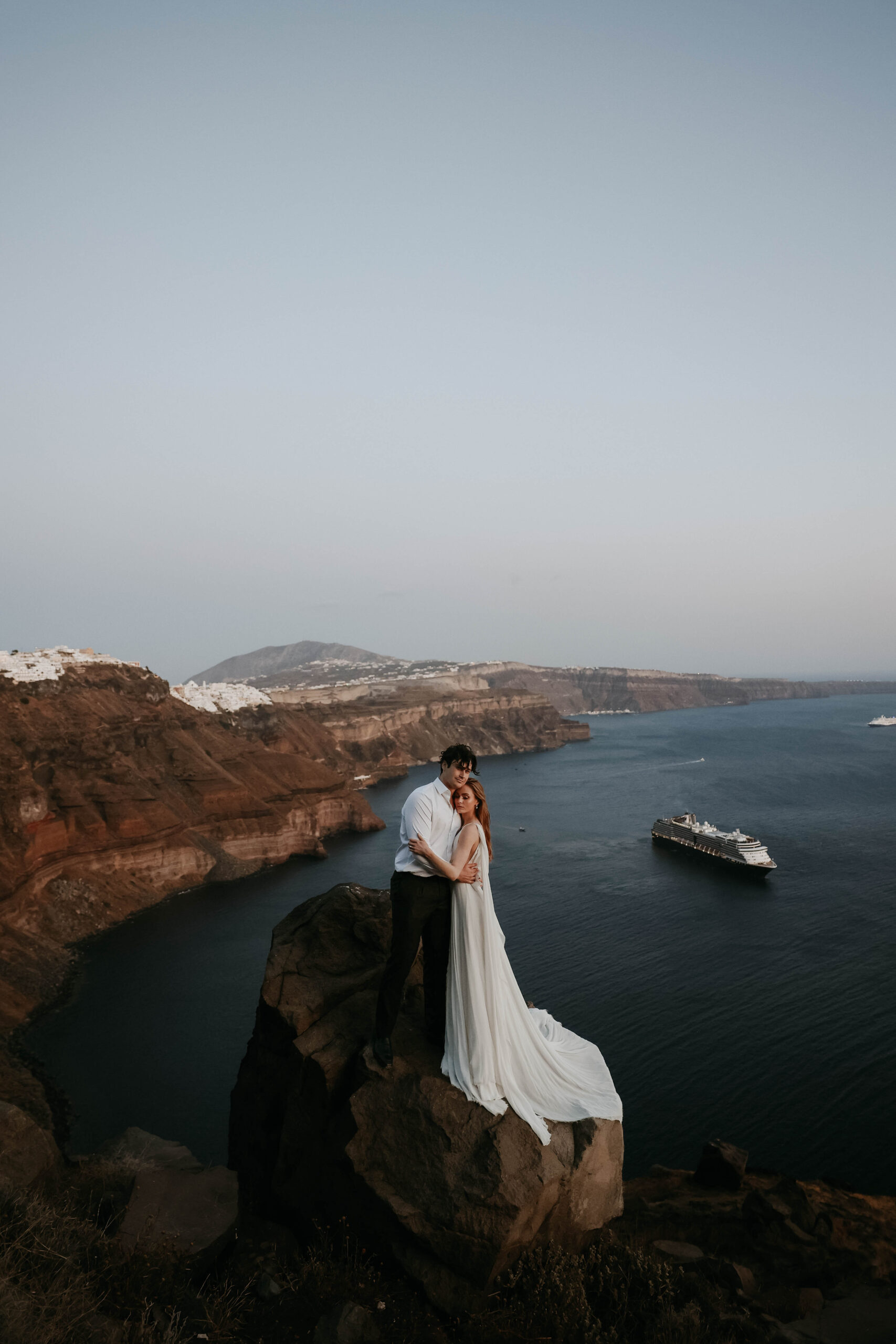 bride and groom holding each other on a cliff for Santorini Greece elopement