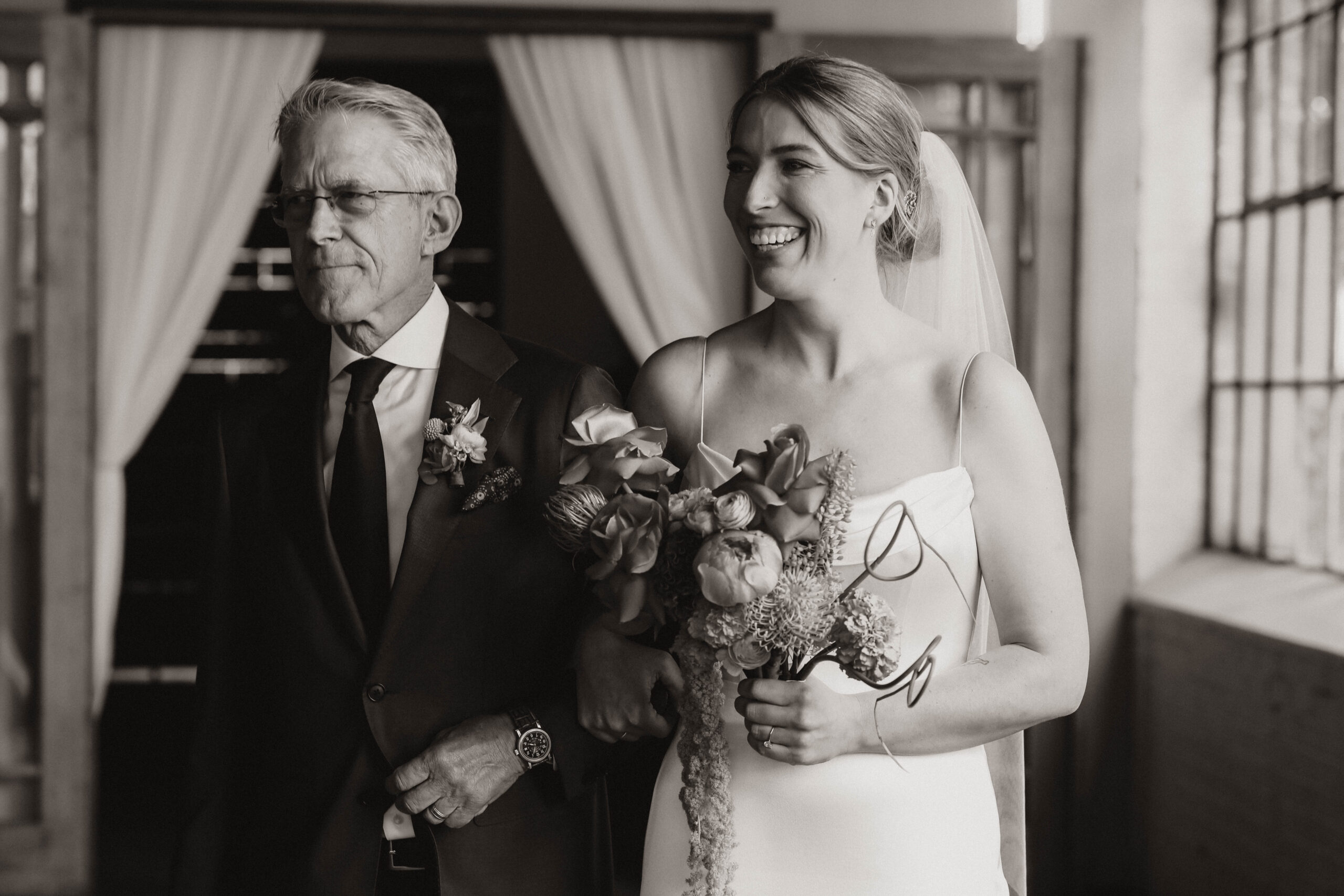 bride smiling as she walks down the aisle with her dad 