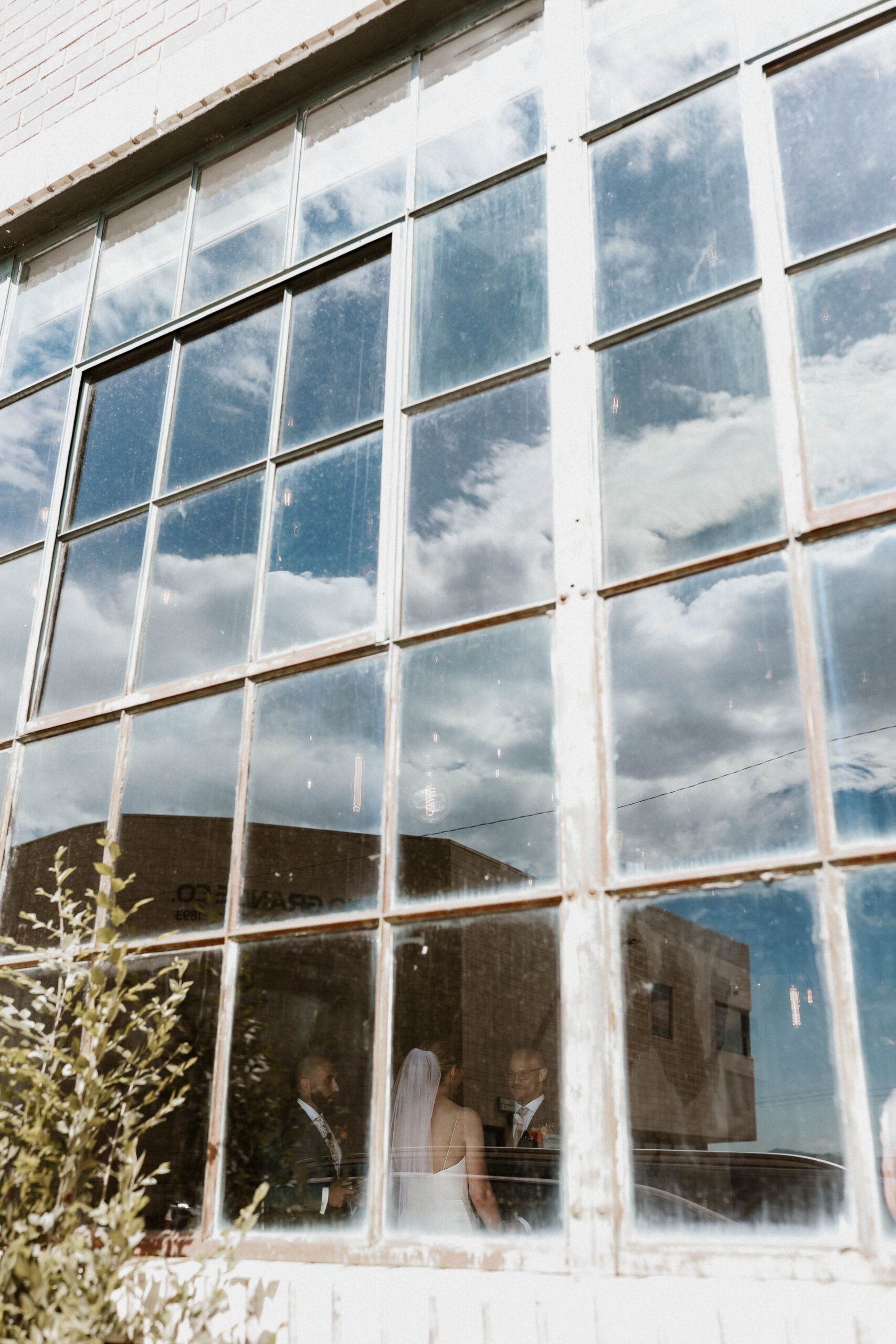 bride and groom through a tall window at one of the most perfect Denver Colorado venues