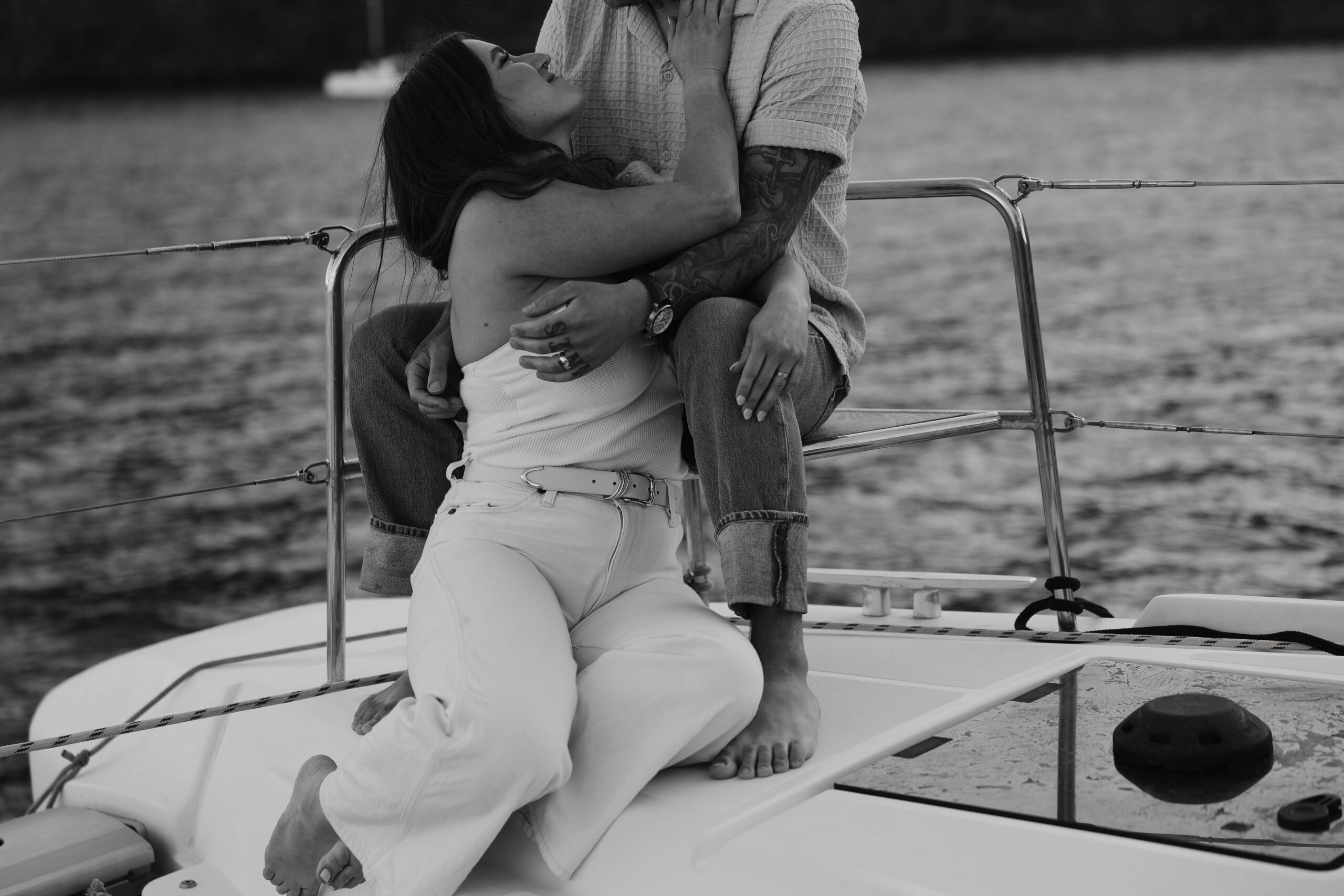 a woman sitting at her man's feet on a boat during their couples session