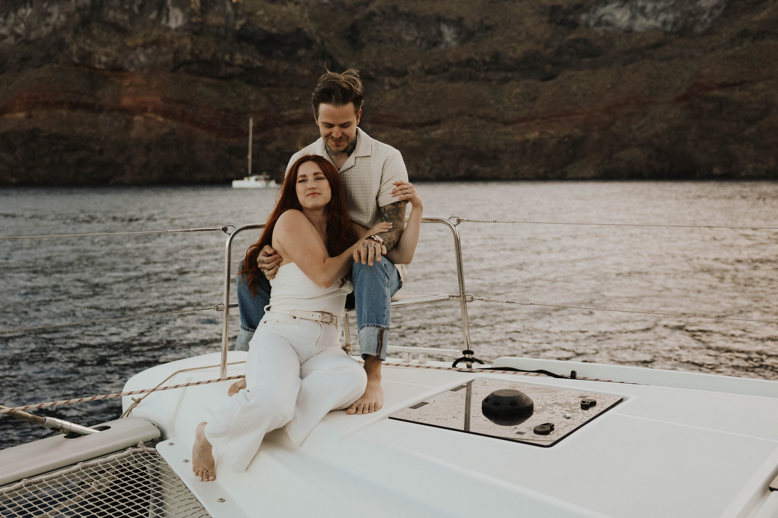 a woman sitting between a mans legs on a boat during their couples session