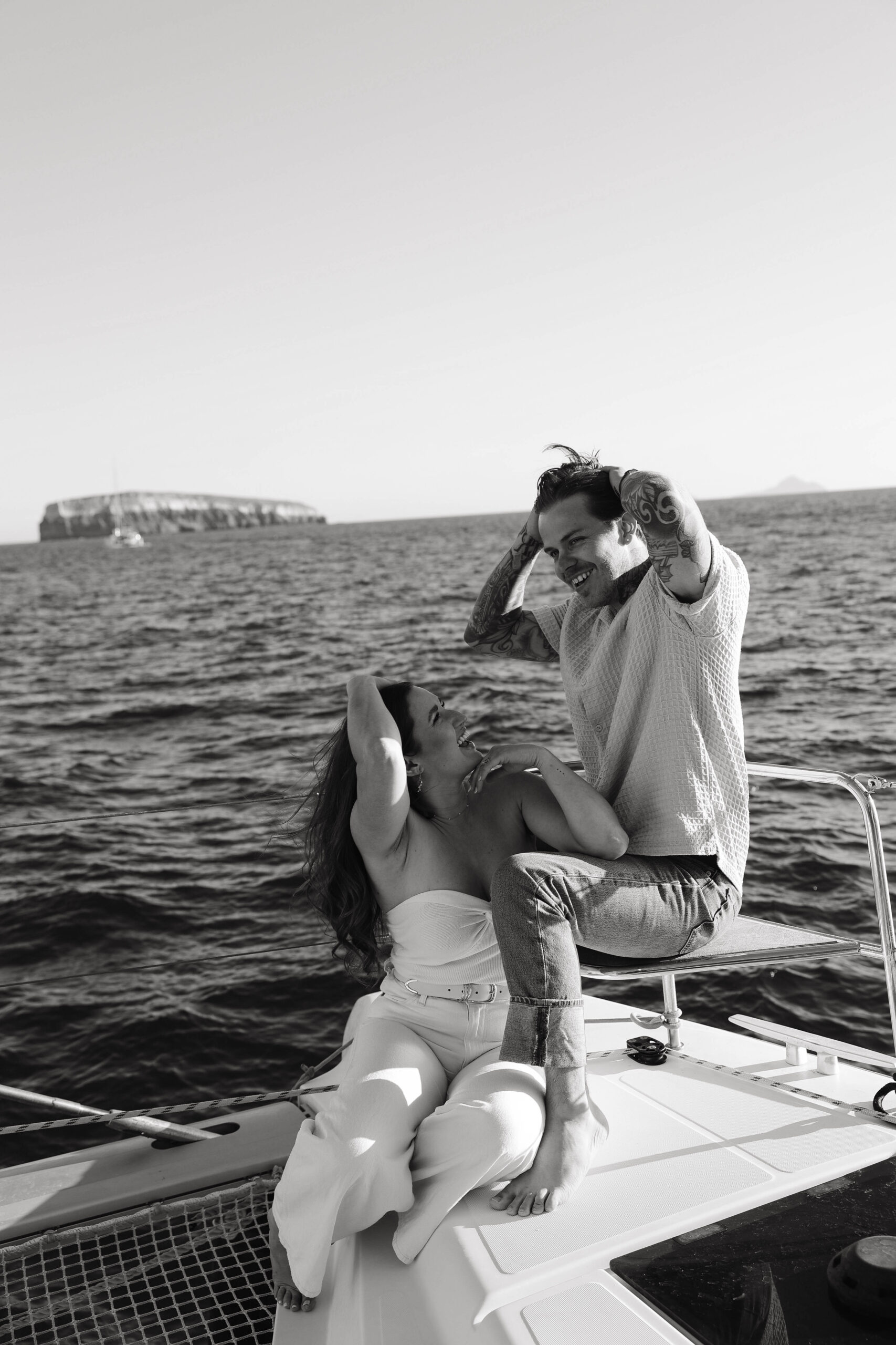 a couple holding their hair back from the wind on a boat during their couples session