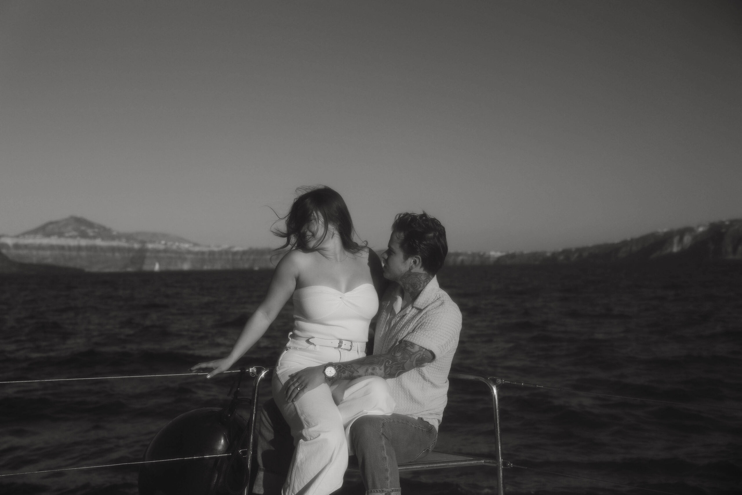 a couple sitting on a Sailboat in Greece during their couples session