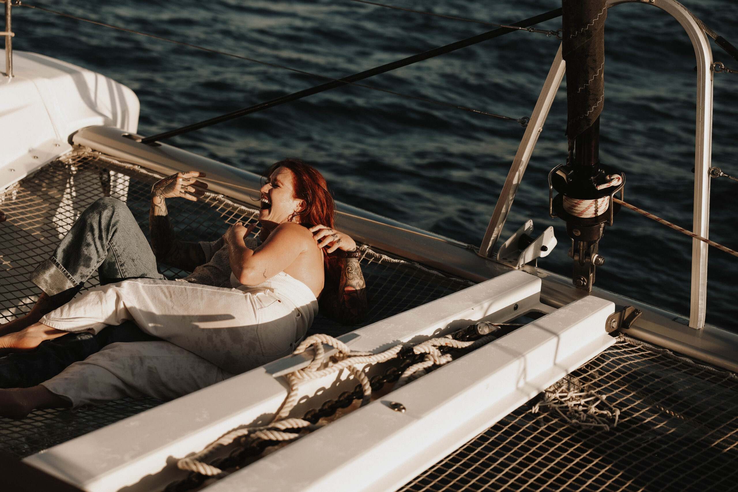 a couple laying together while laughing on a boat getting wet from the waves