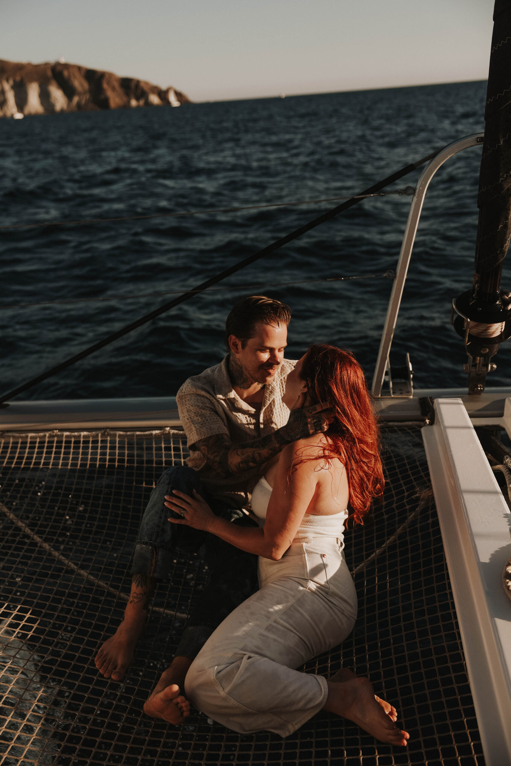 a couple laying on the net on a sailboat together 