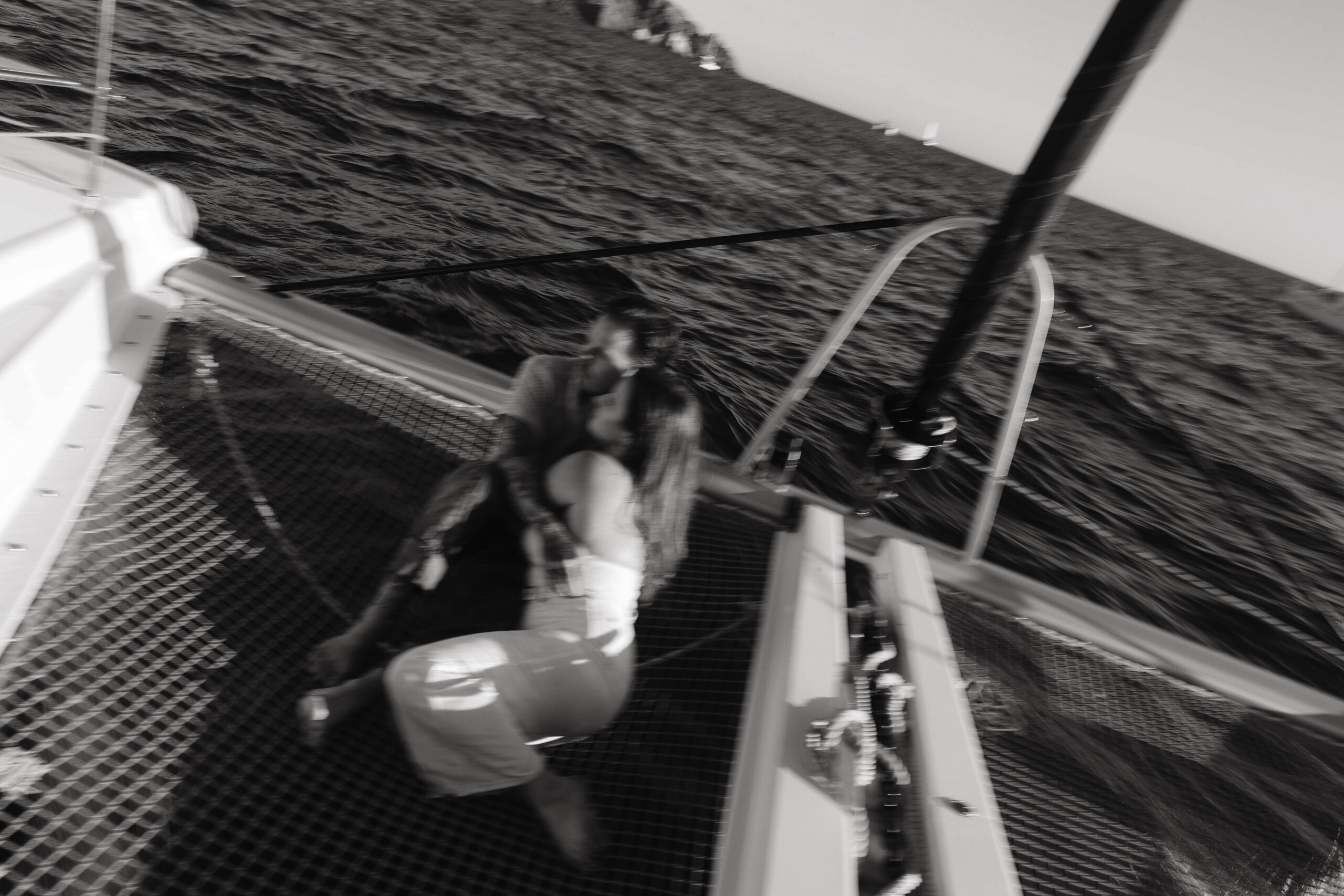 a blurry image of a couple sitting together in the net of a sailboat during their couples session