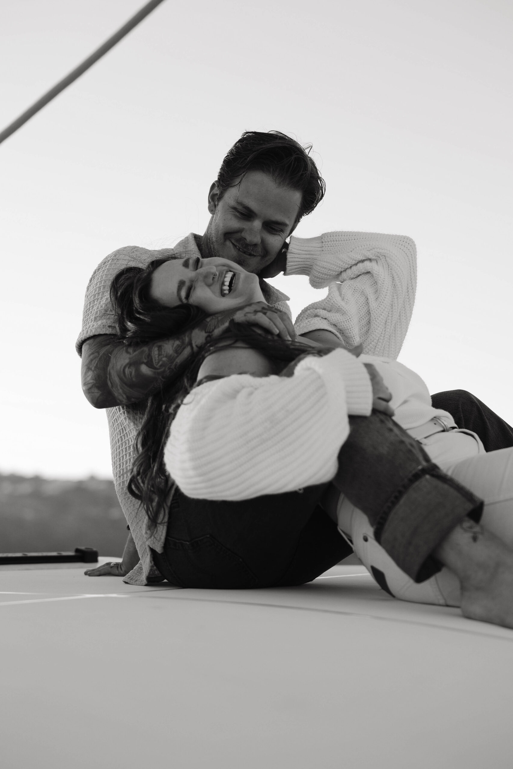 a couple laughing together as they sit on a boat during their couples session