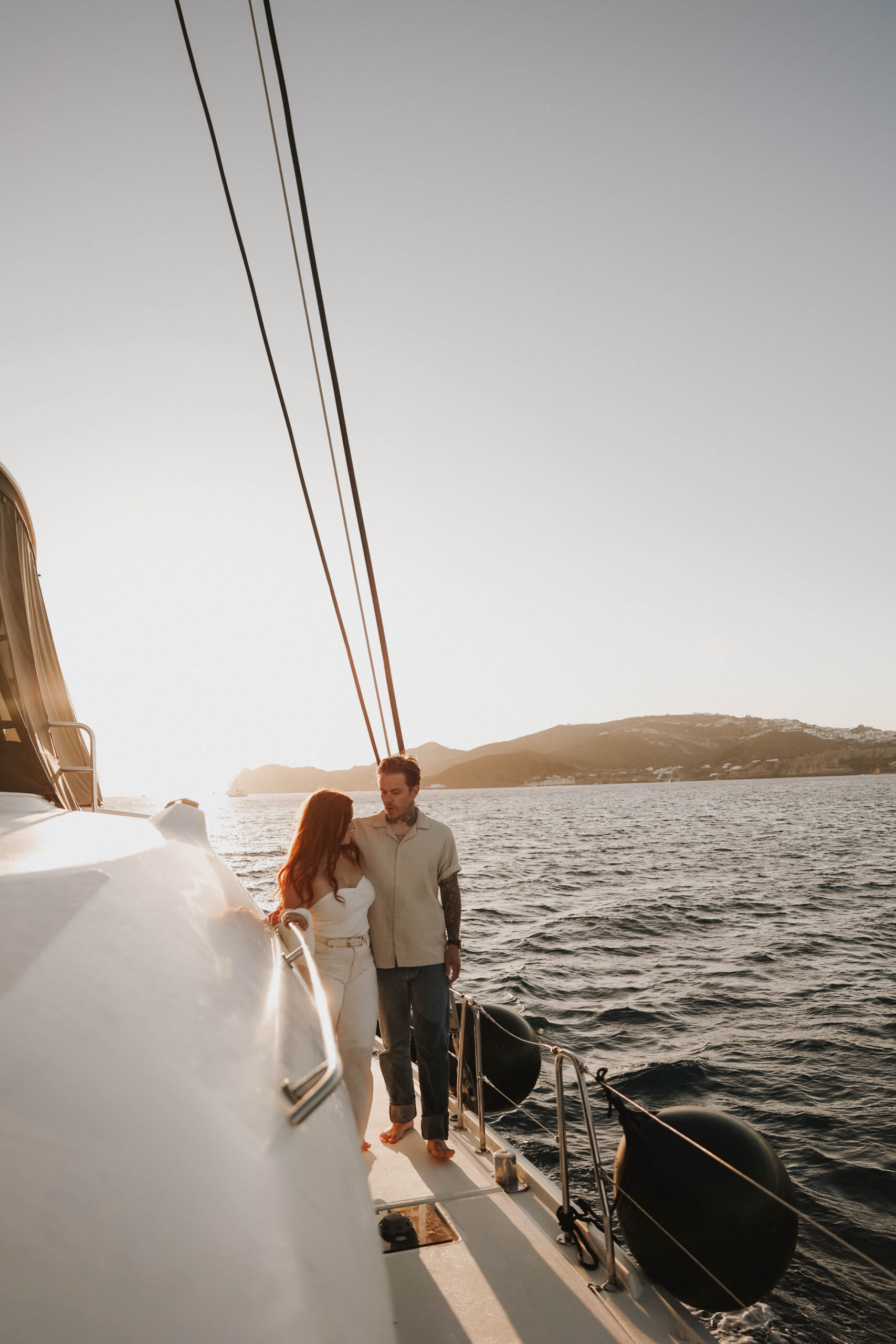 a couple standing on a sailboat together in the sea during their couples session