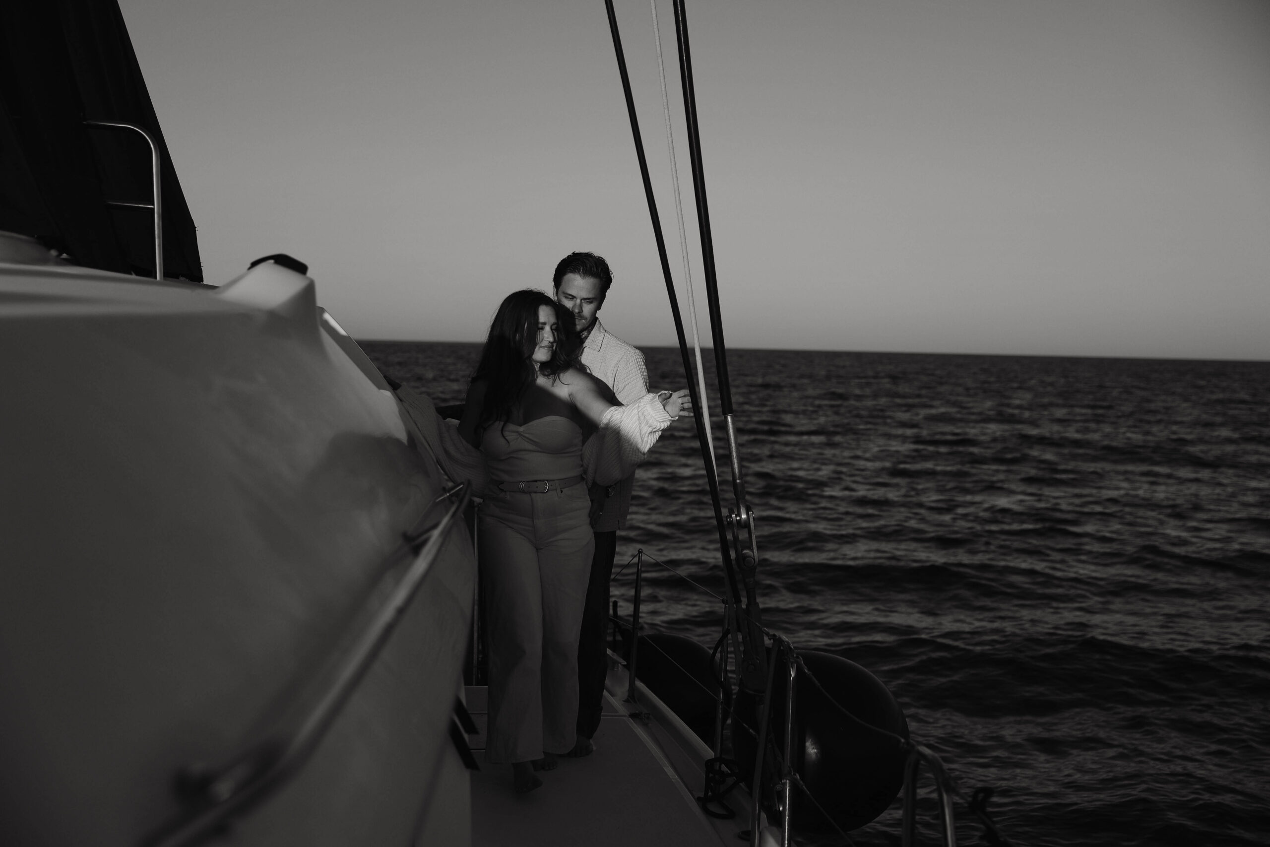 a man standing behind a woman on a boat in Greece during their couples session