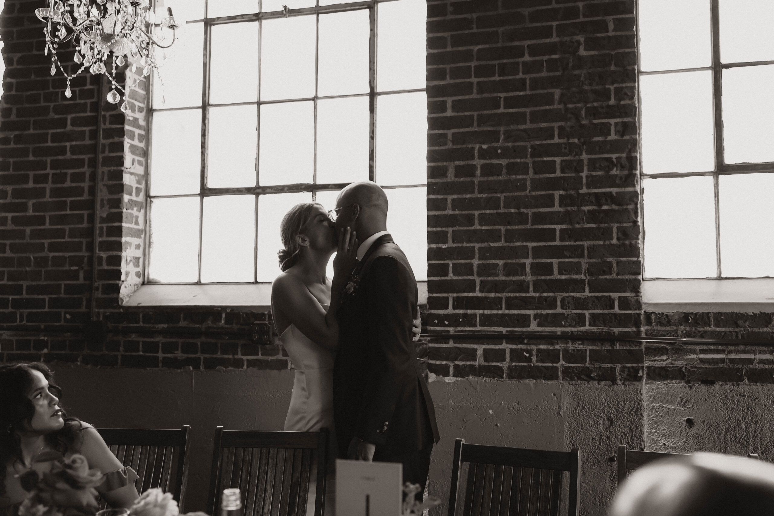 bride and groom kissing at reception table 