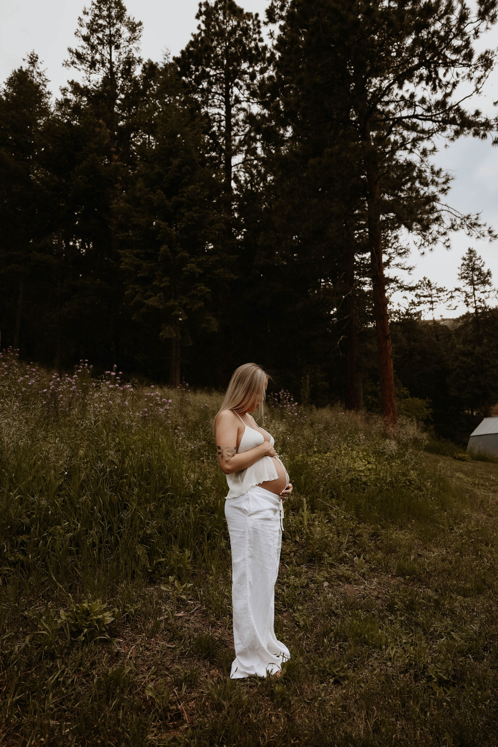 a pregnant woman holding her tummy in her backyard 