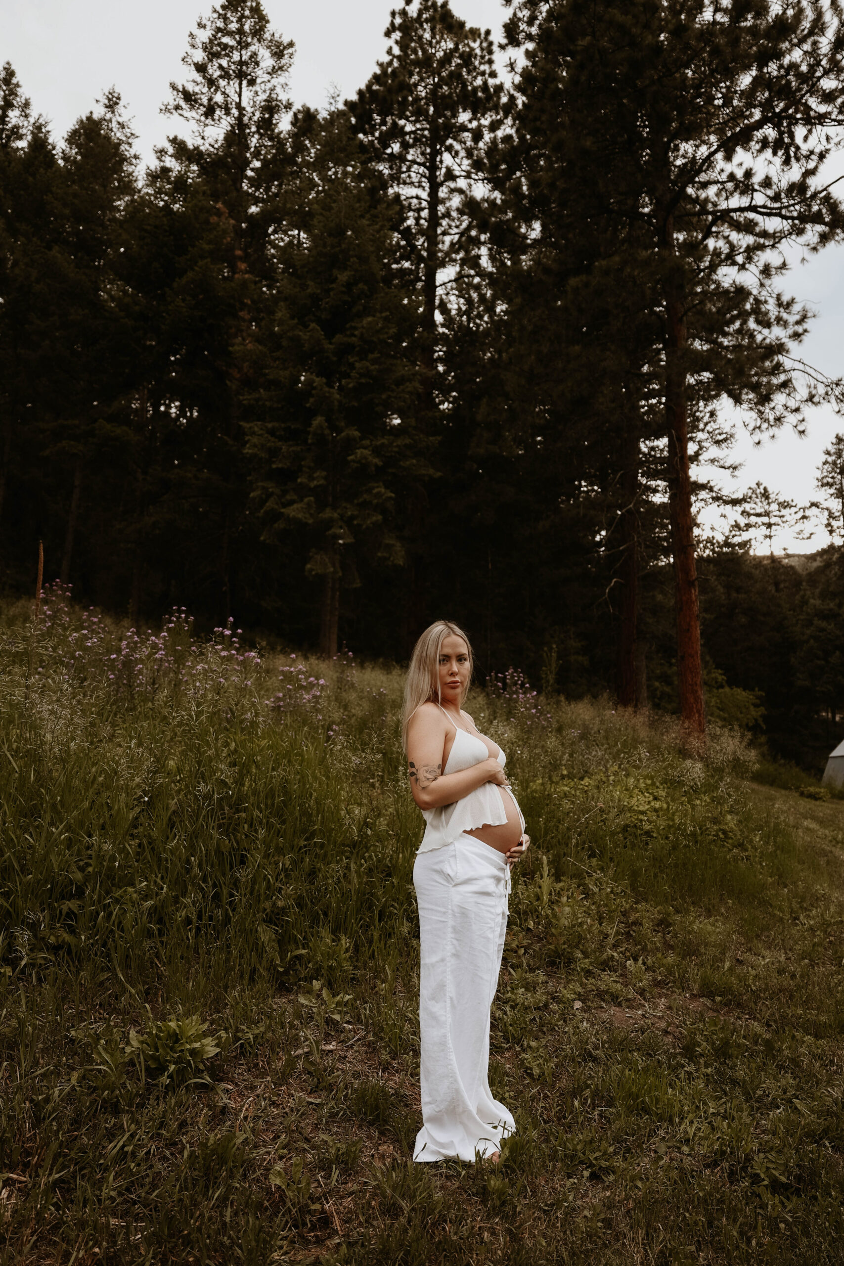 a pregnant woman in her backyard holding her belly