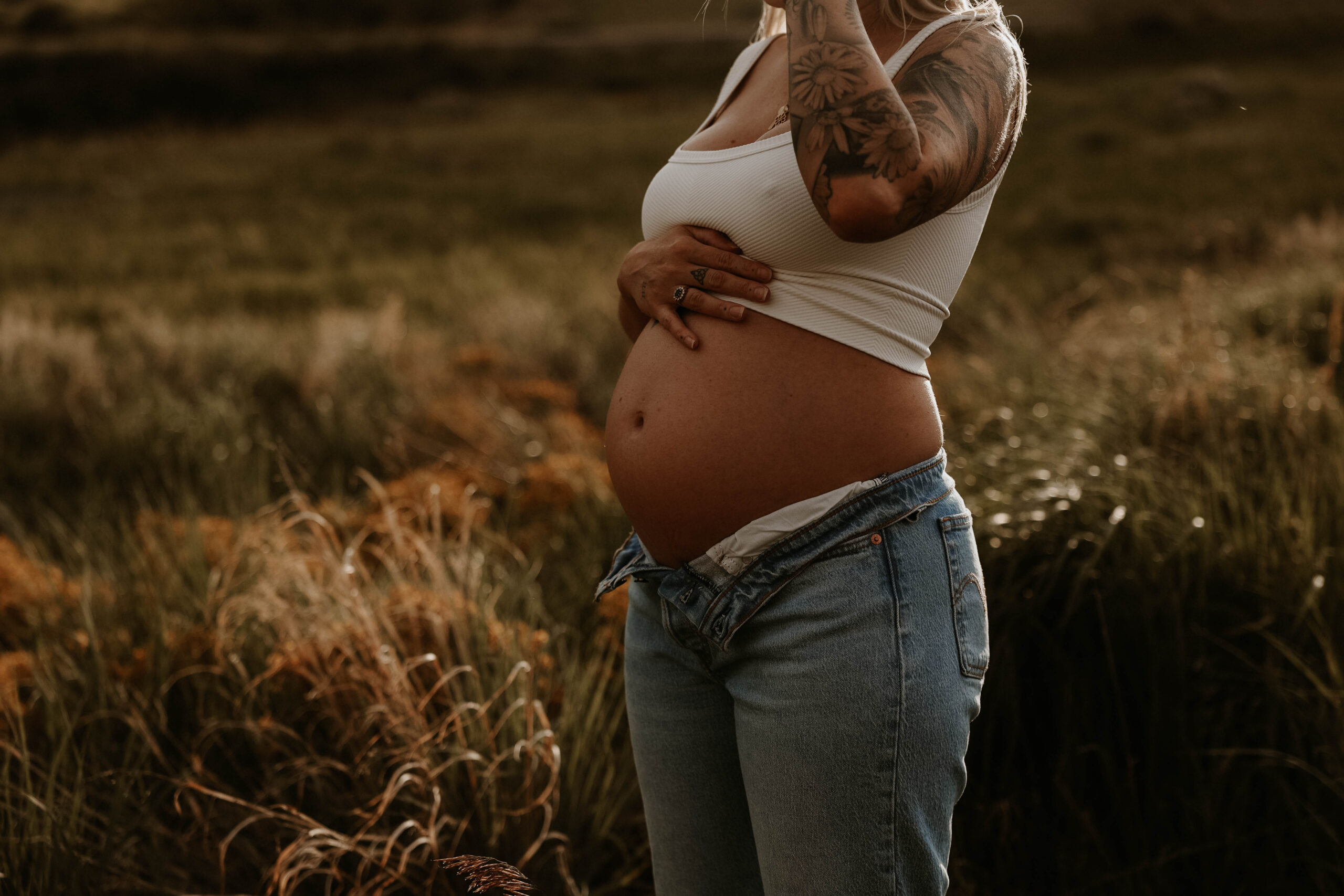 a pregnant woman in a field during a jeans maternity shoot 