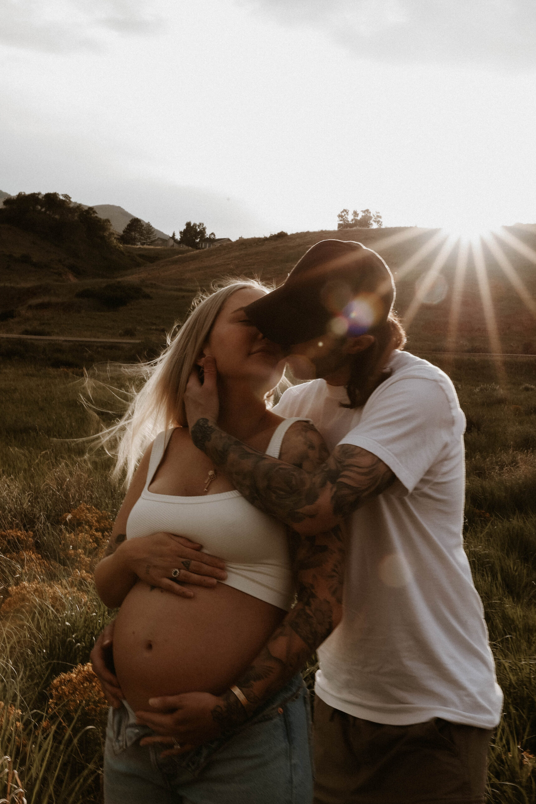 a couple with their faces together as the sun hits them during a maternity photoshoot 