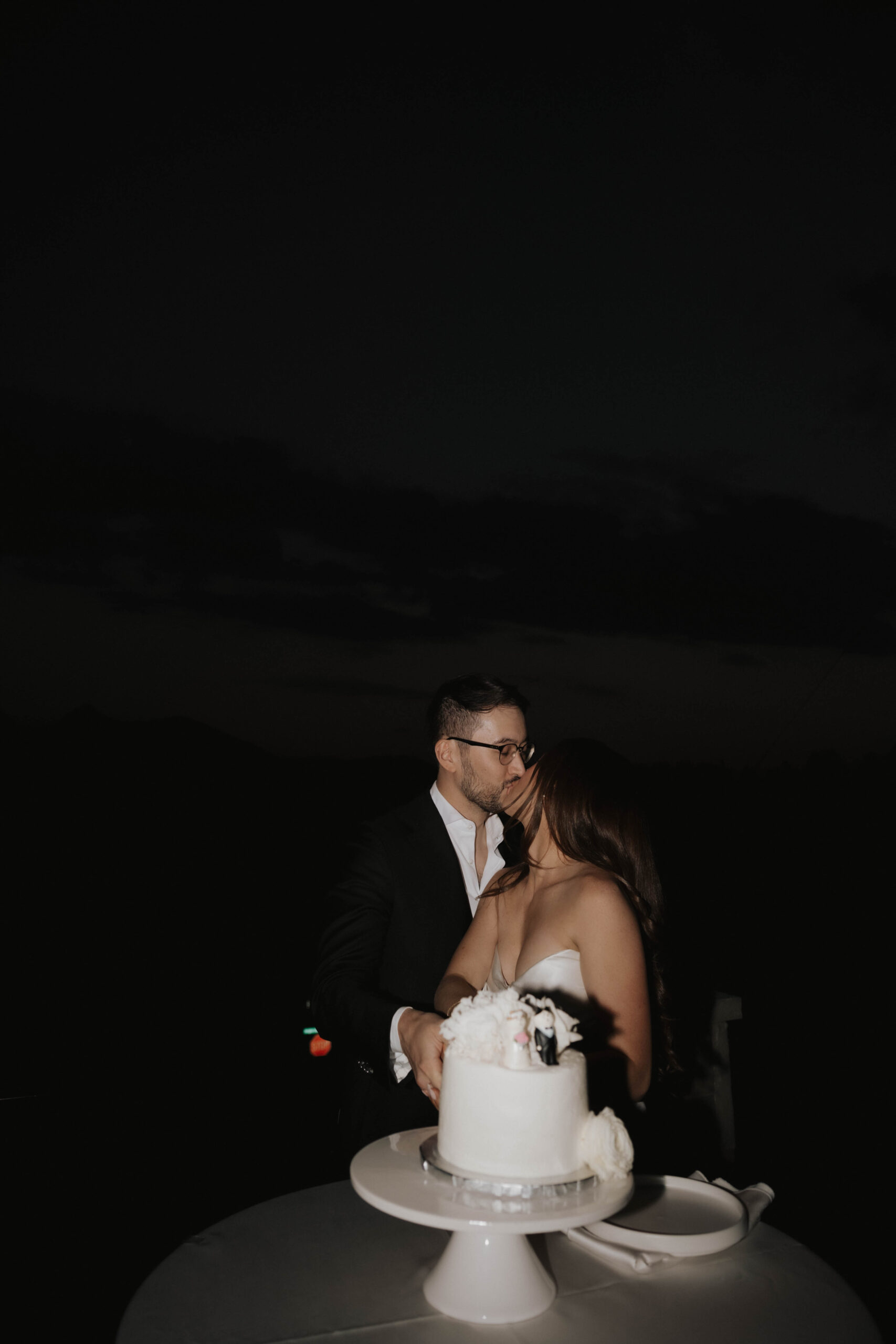 bride and groom kissing in front of their wedding cake 