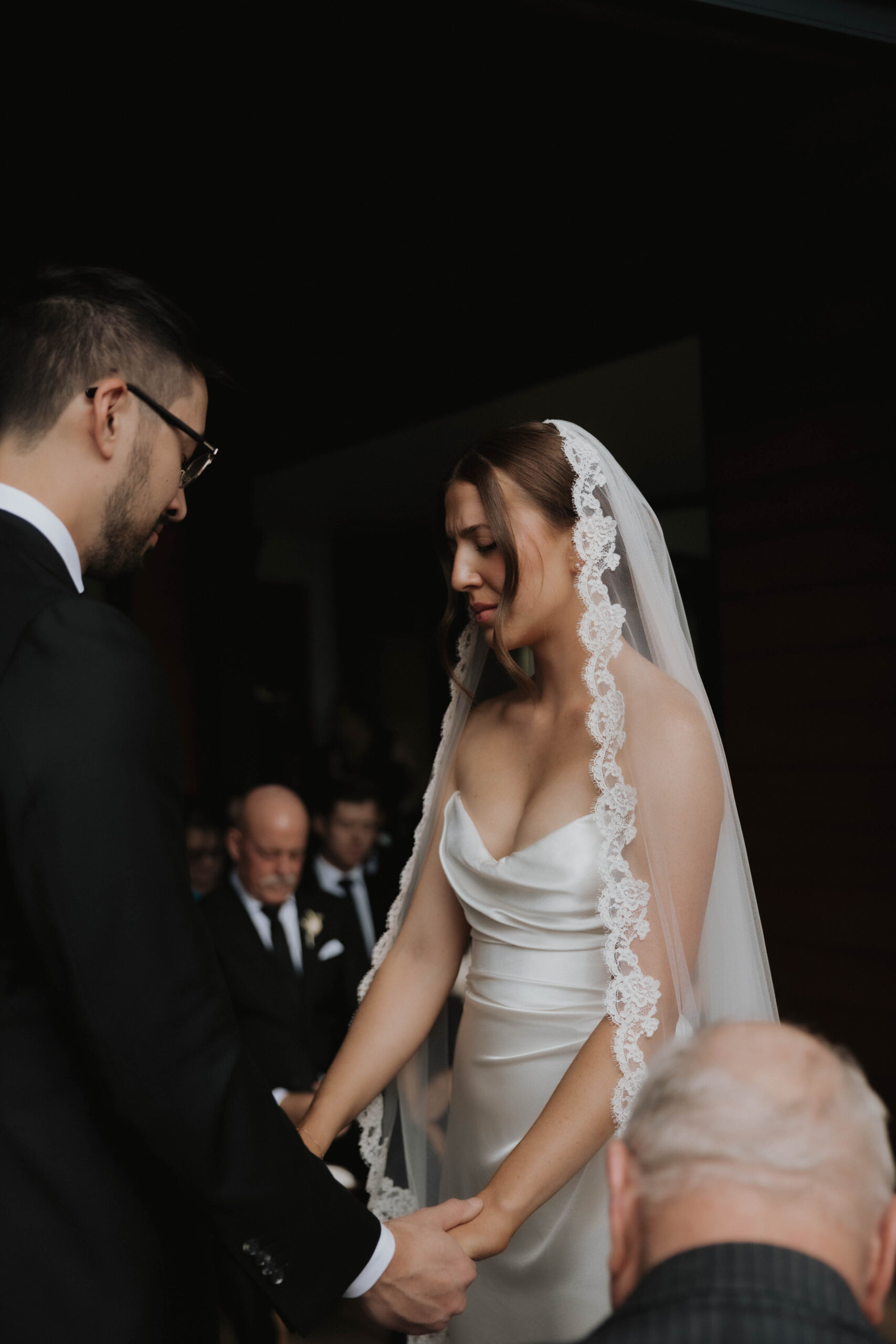 bride and groom holding hands and closing their eyes at the altar 