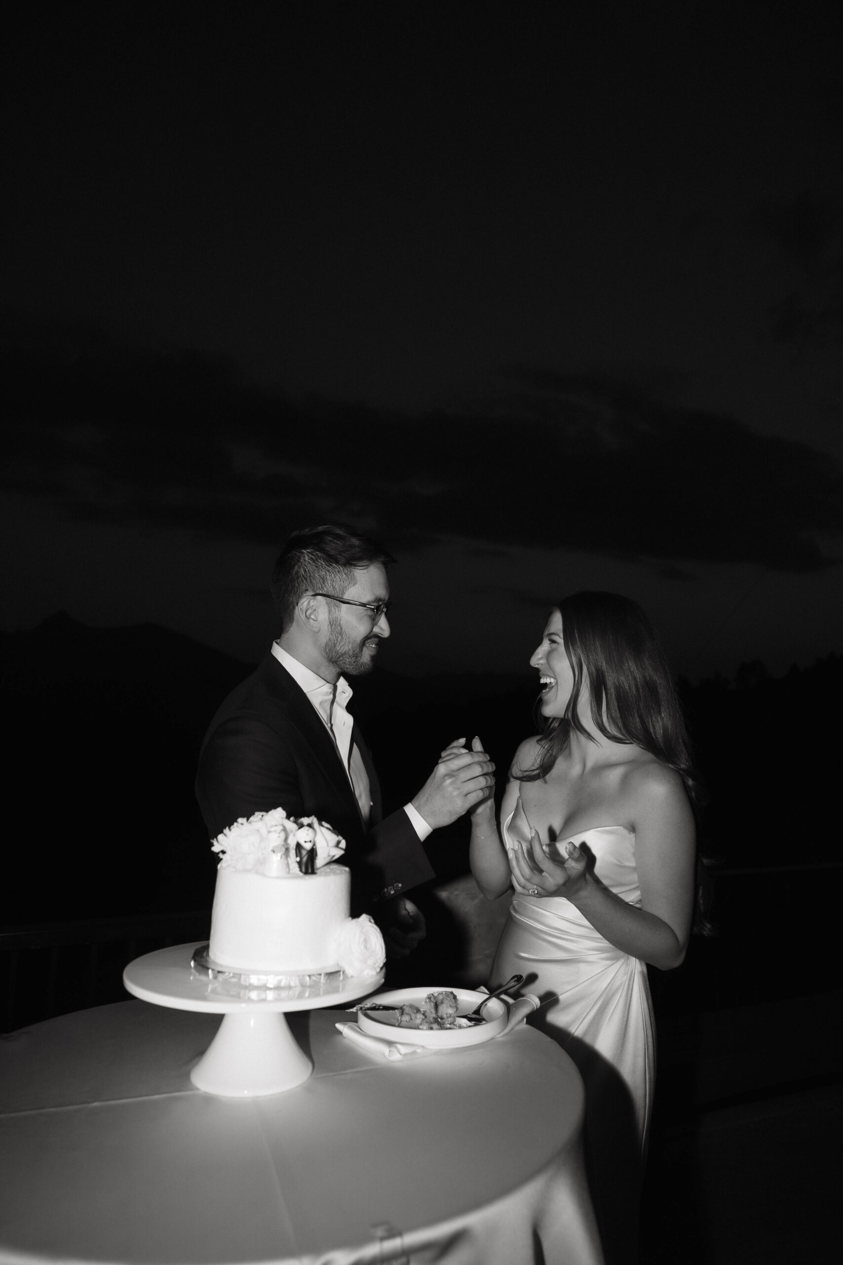 bride and groom laughing while cutting their Colorado micro wedding cake 