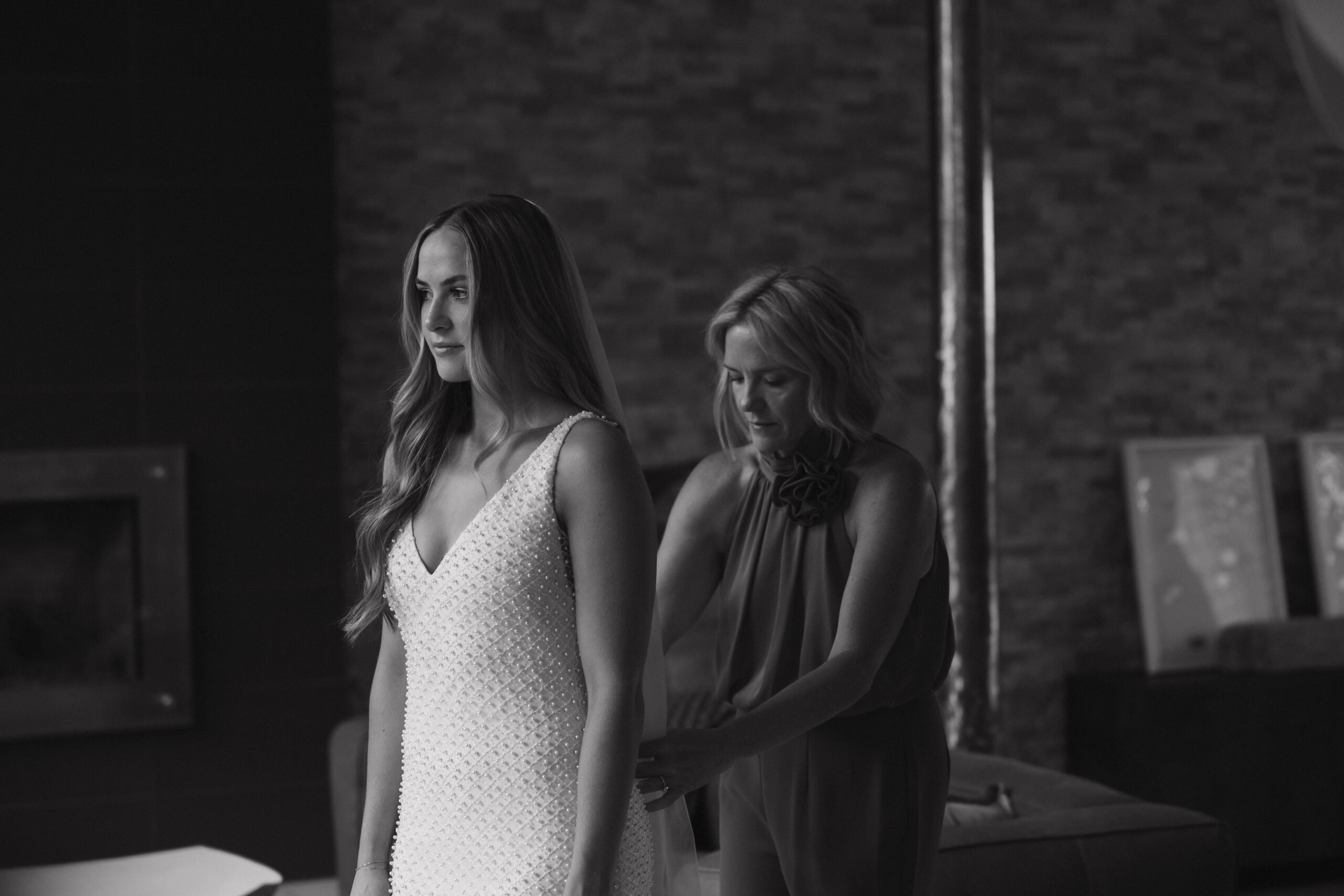 bride's mom helping her with her dress