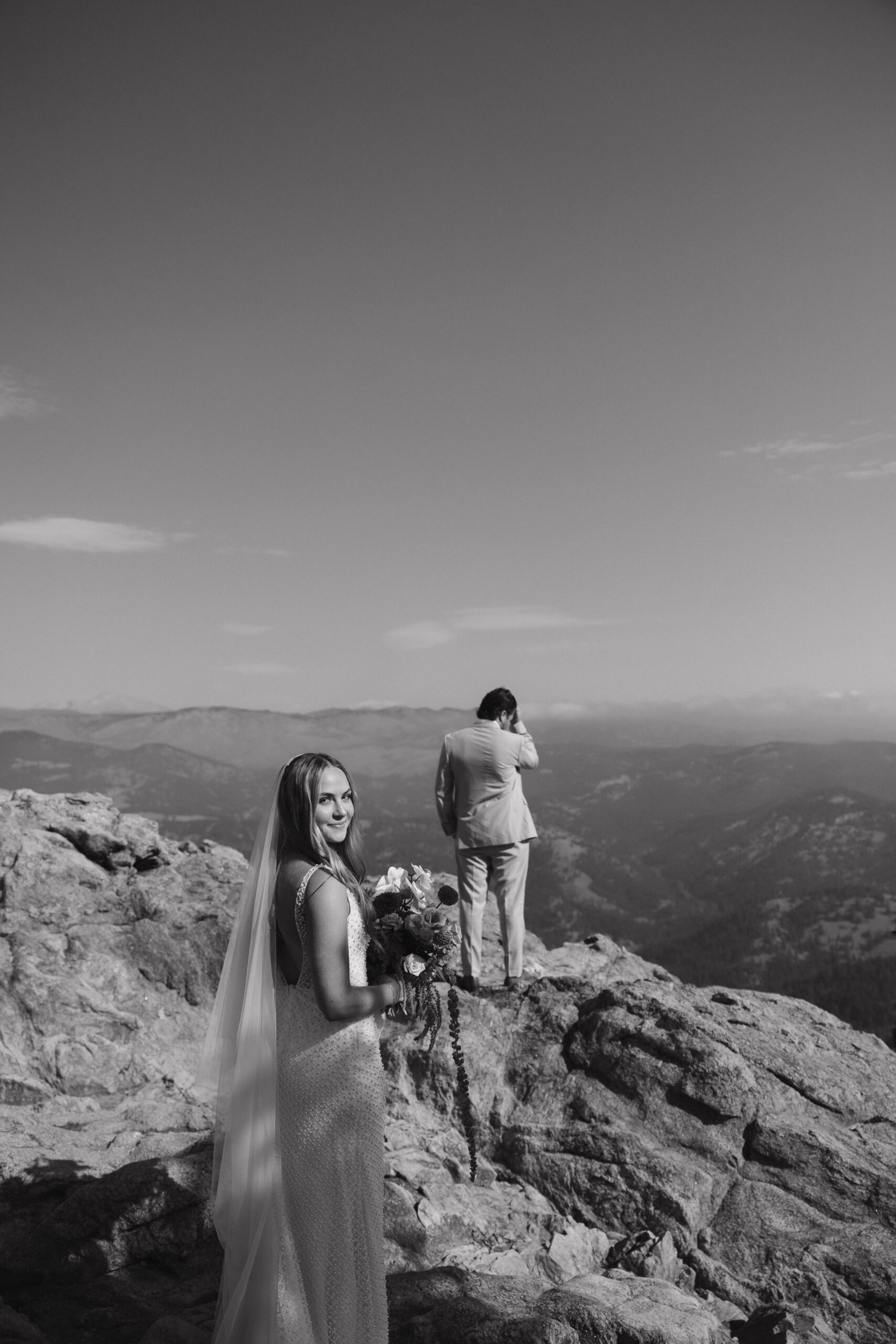 bride standing behind the groom before the first look