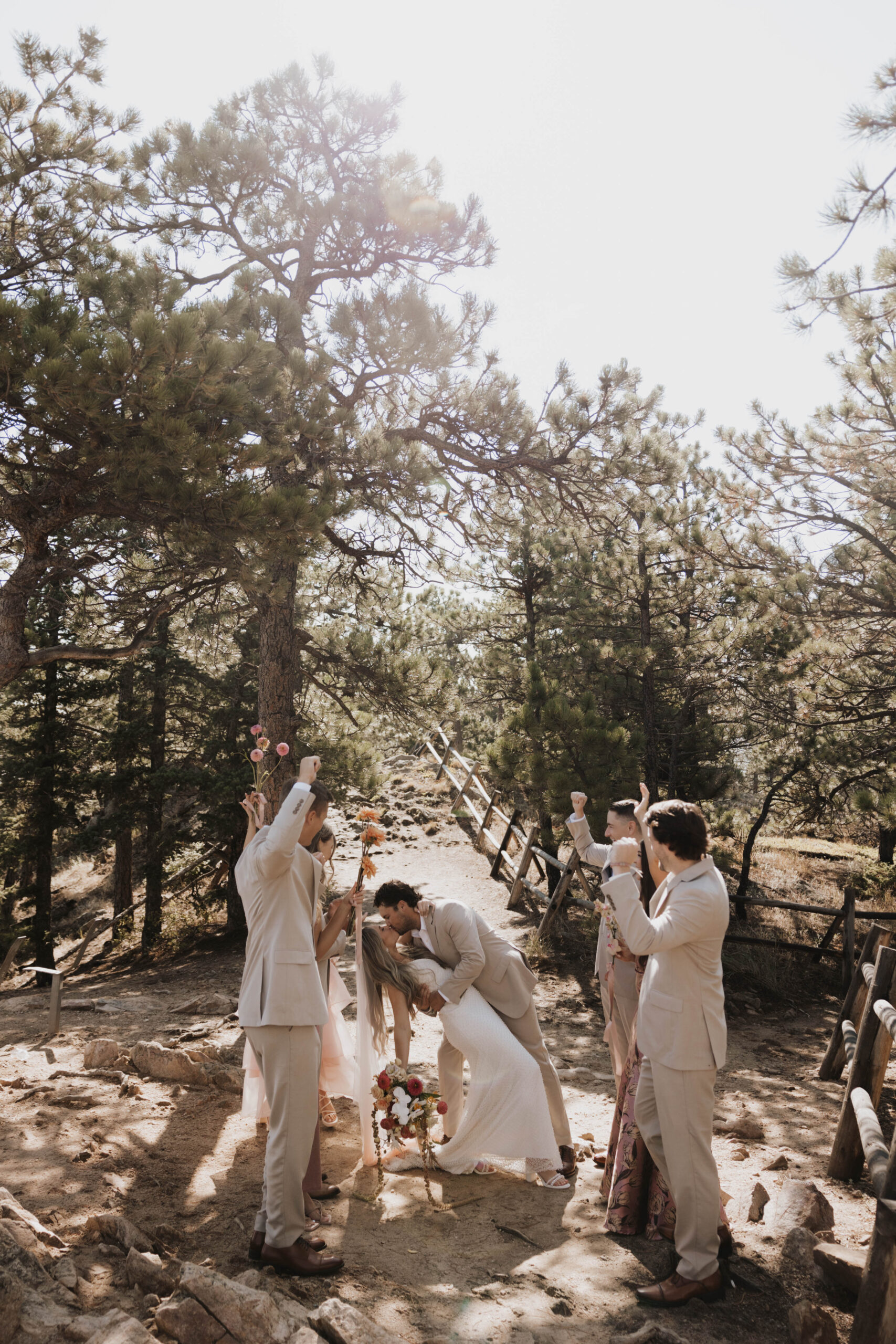 bride and groom kissing with groomsmen around them 