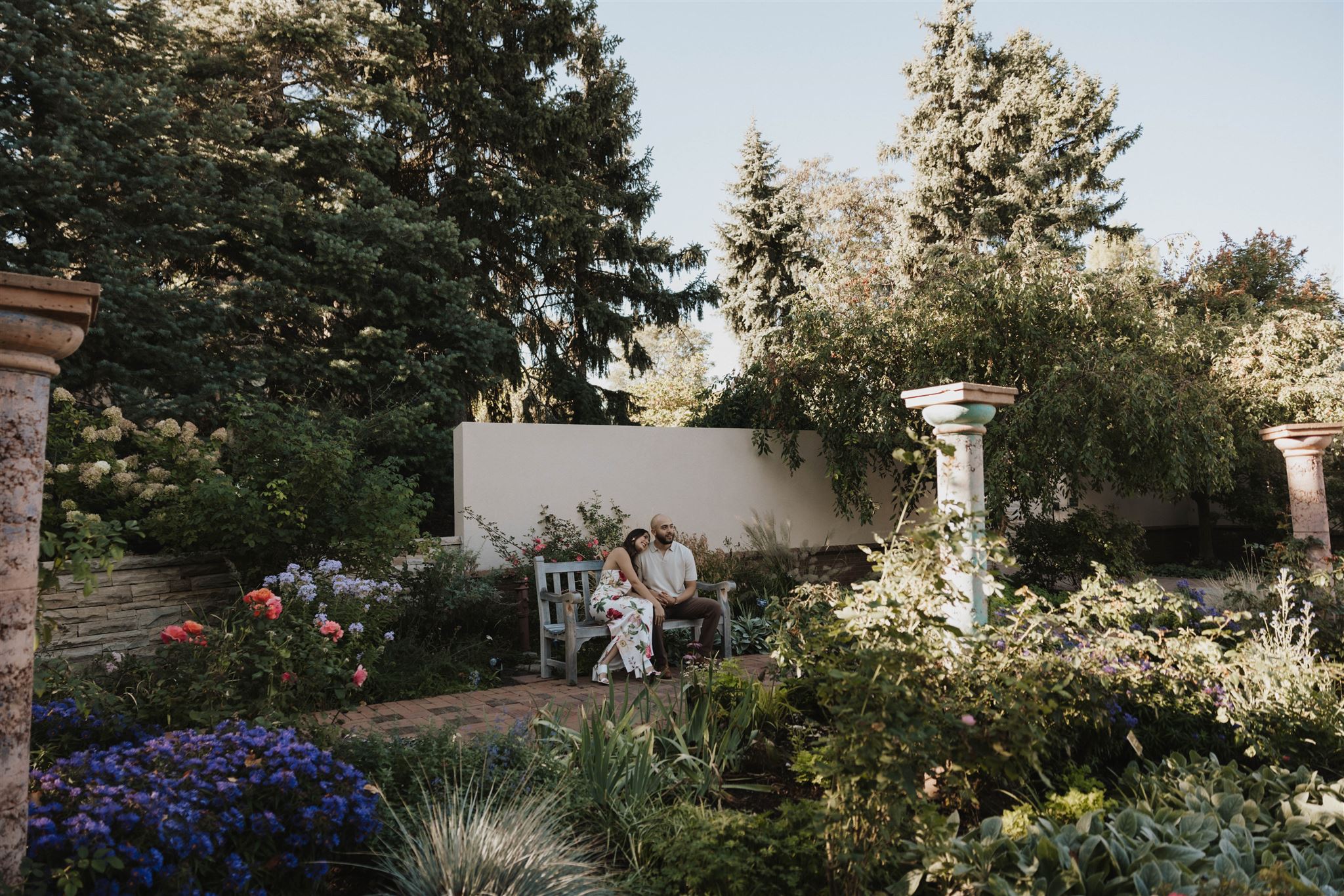 a couple sitting together on a bench in a beautiful garden during engagement a photoshoot 