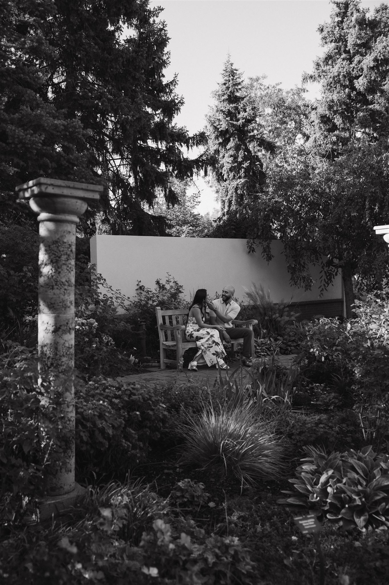 a couple sitting on a bench in the gardens 