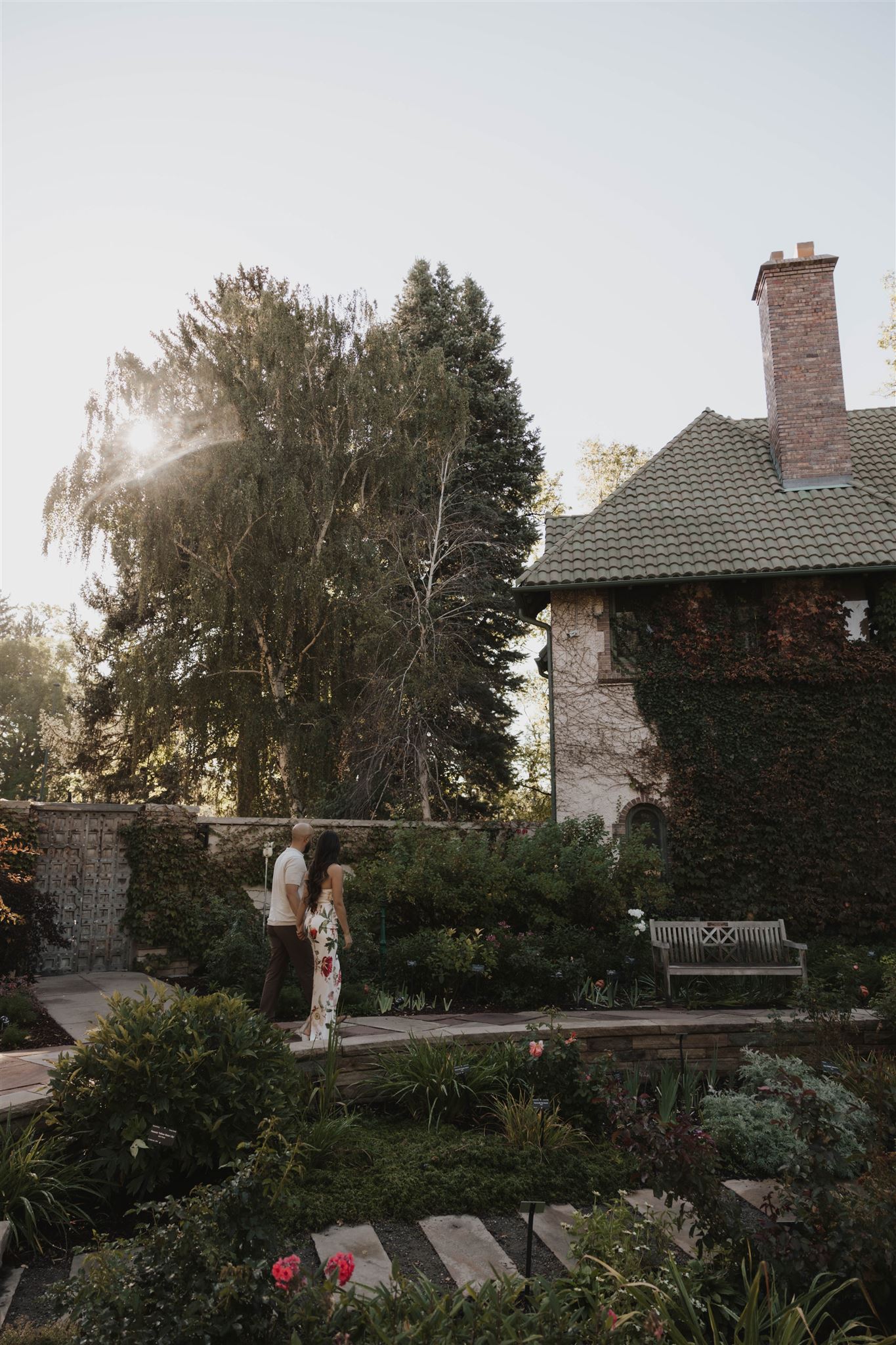 a couple walking towards an ivy covered building in the garden 