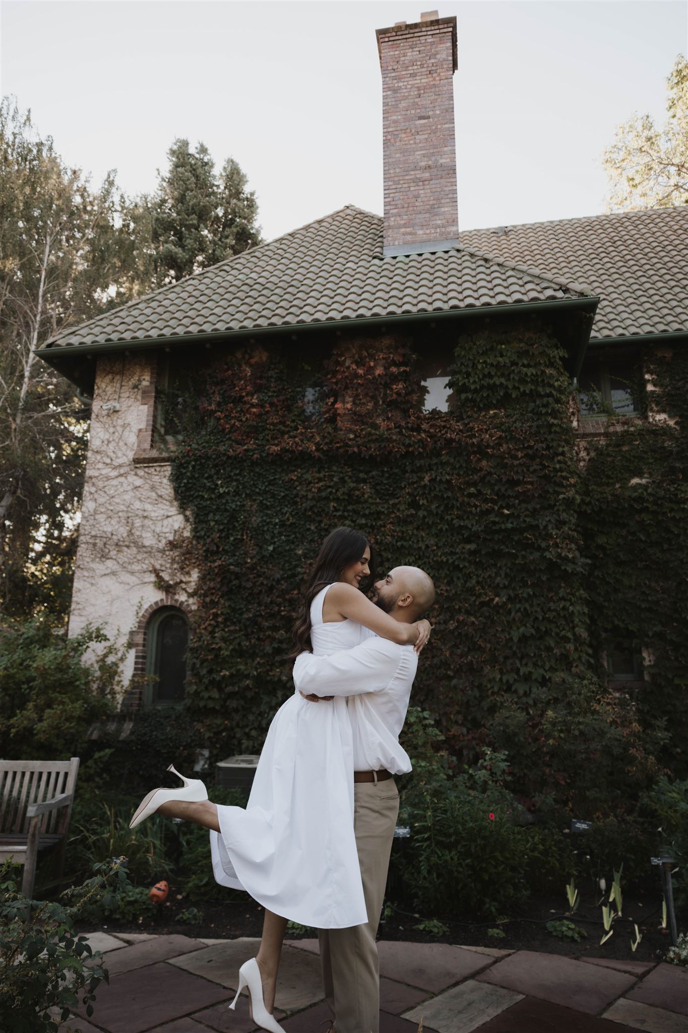 a man holding a woman with her leg kicked out during their Denver Botanic Gardens Engagement Photos