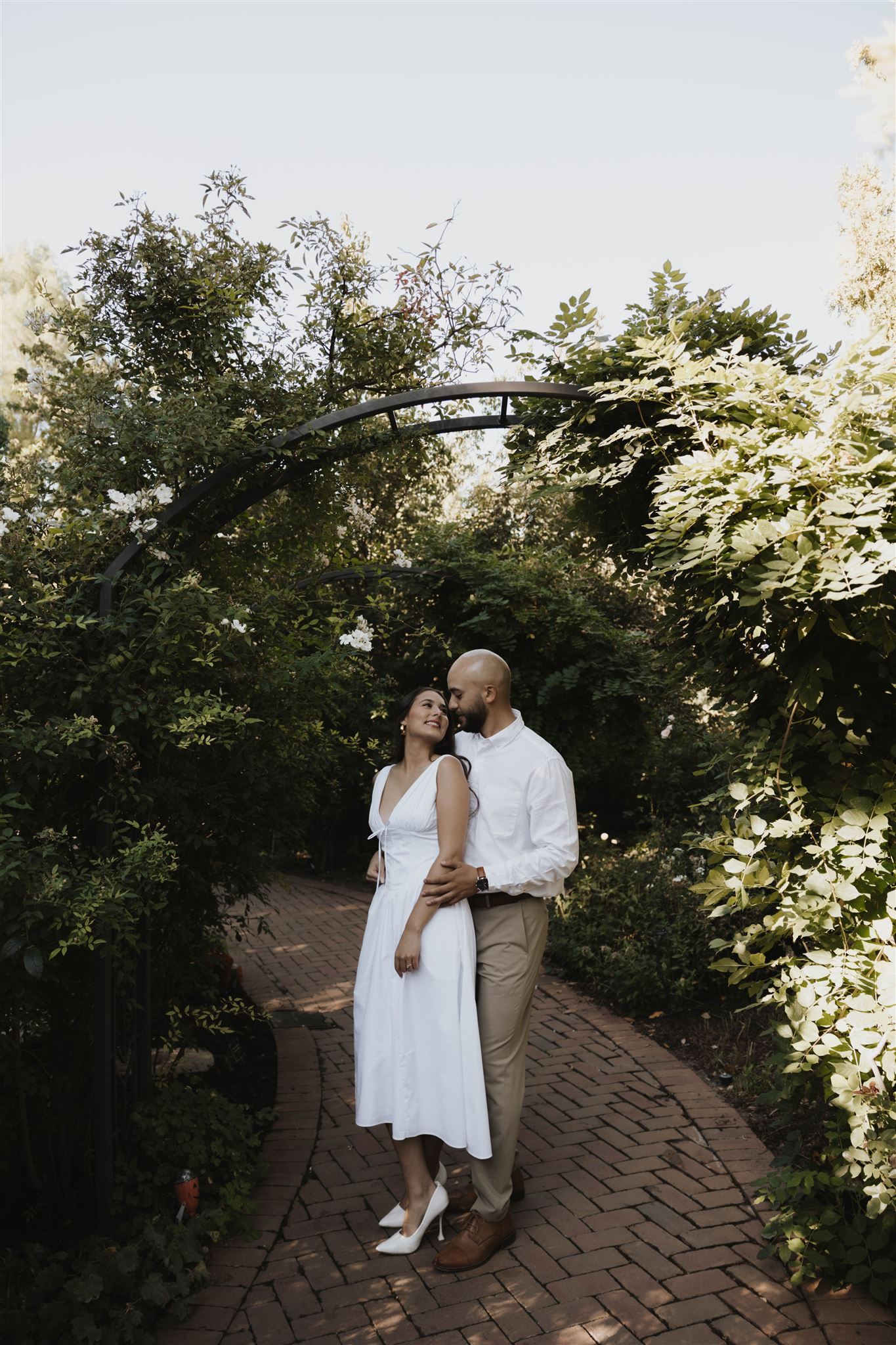 a couple standing under an arch in the garden during their Denver Botanic Gardens Engagement Photos