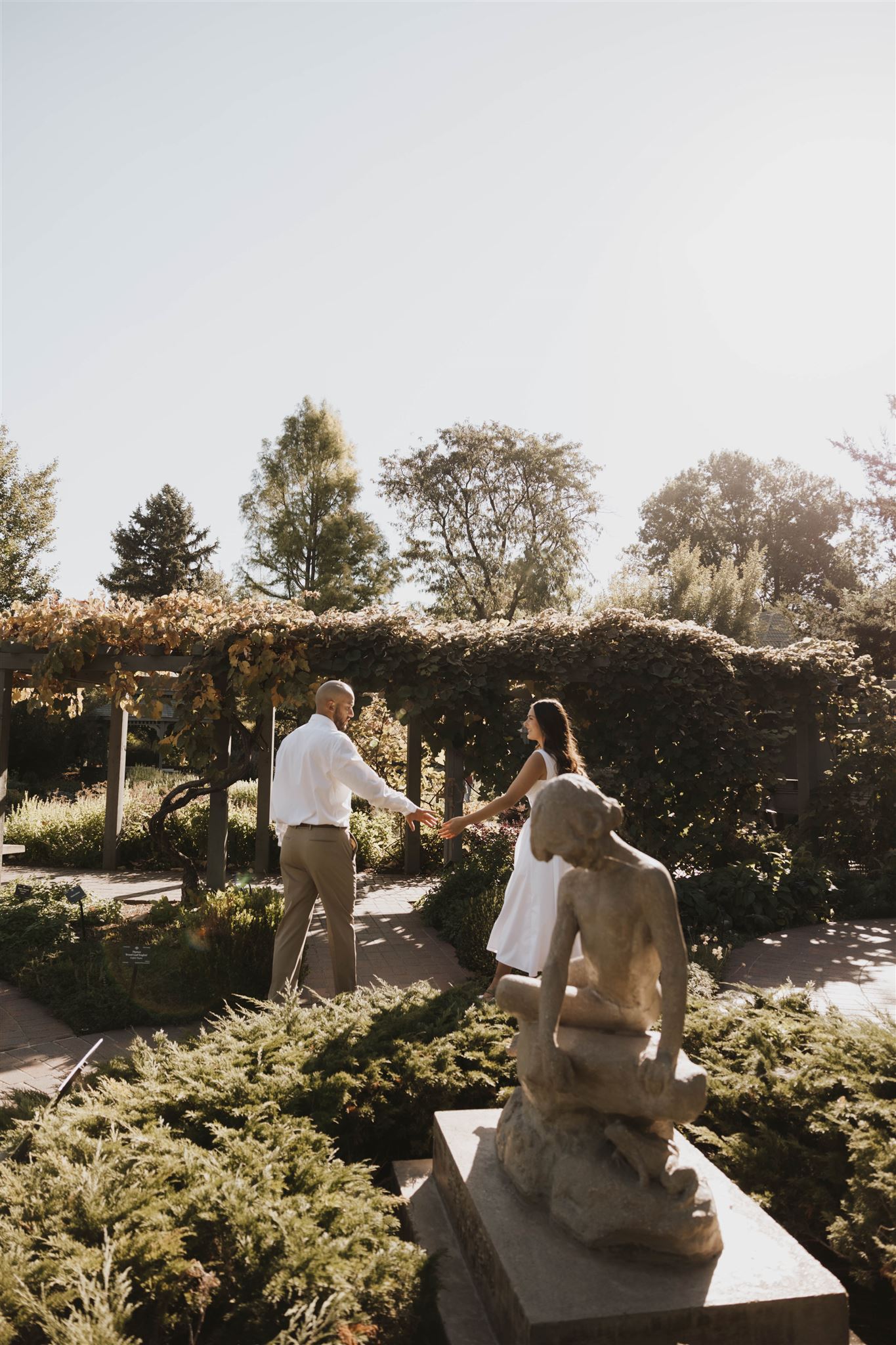 a couple walking through the statue garden during Denver Botanic Gardens Engagement Photos