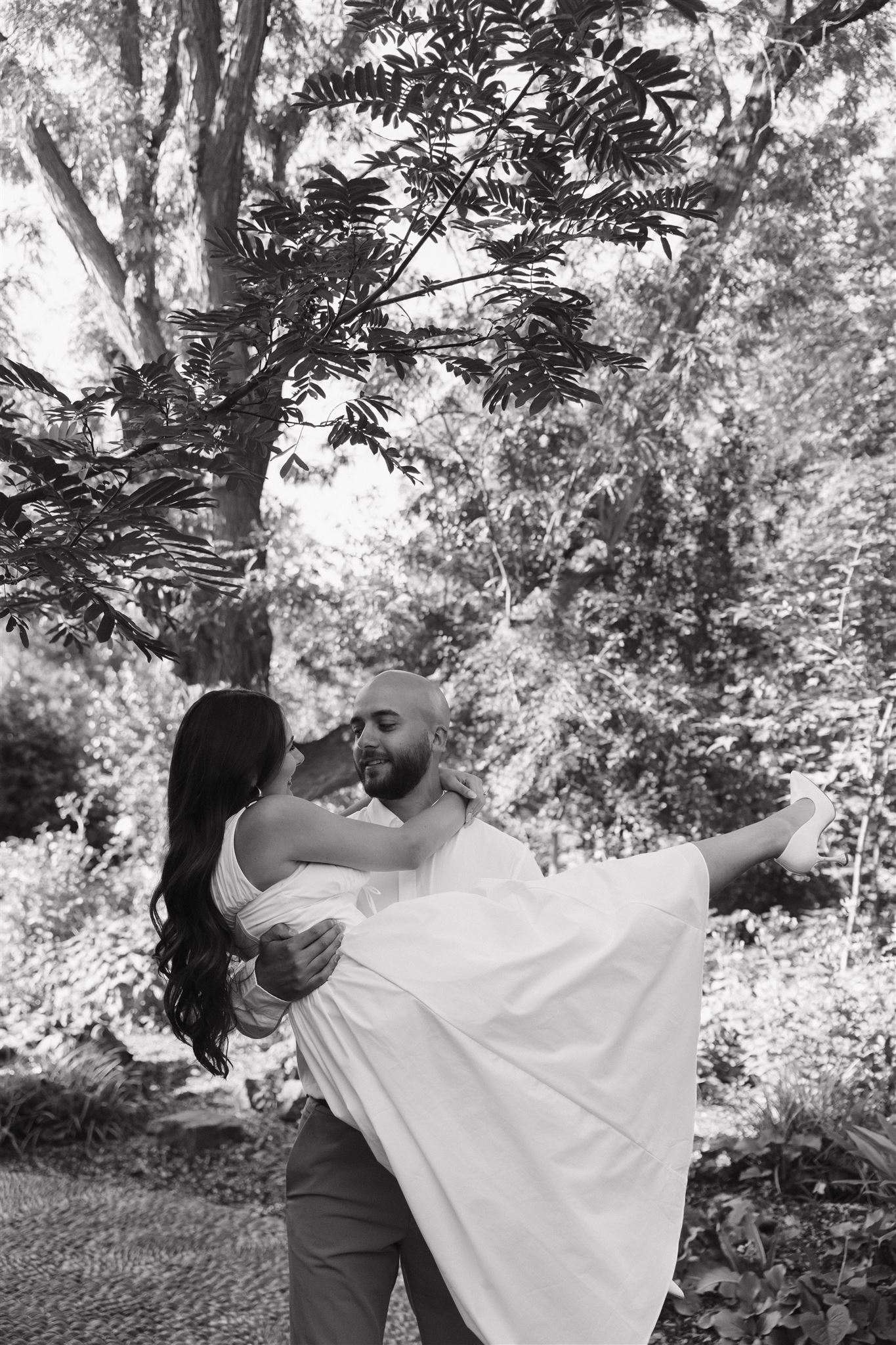 a man holding a woman in a white dress during their Denver Botanic Gardens Engagement Photos