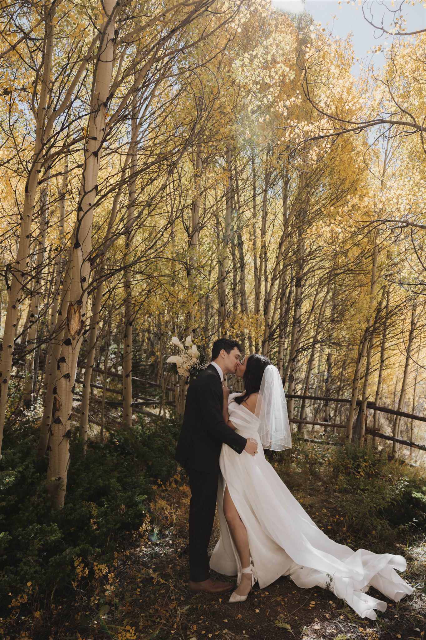 bride and groom kissing in the fall colored woods 