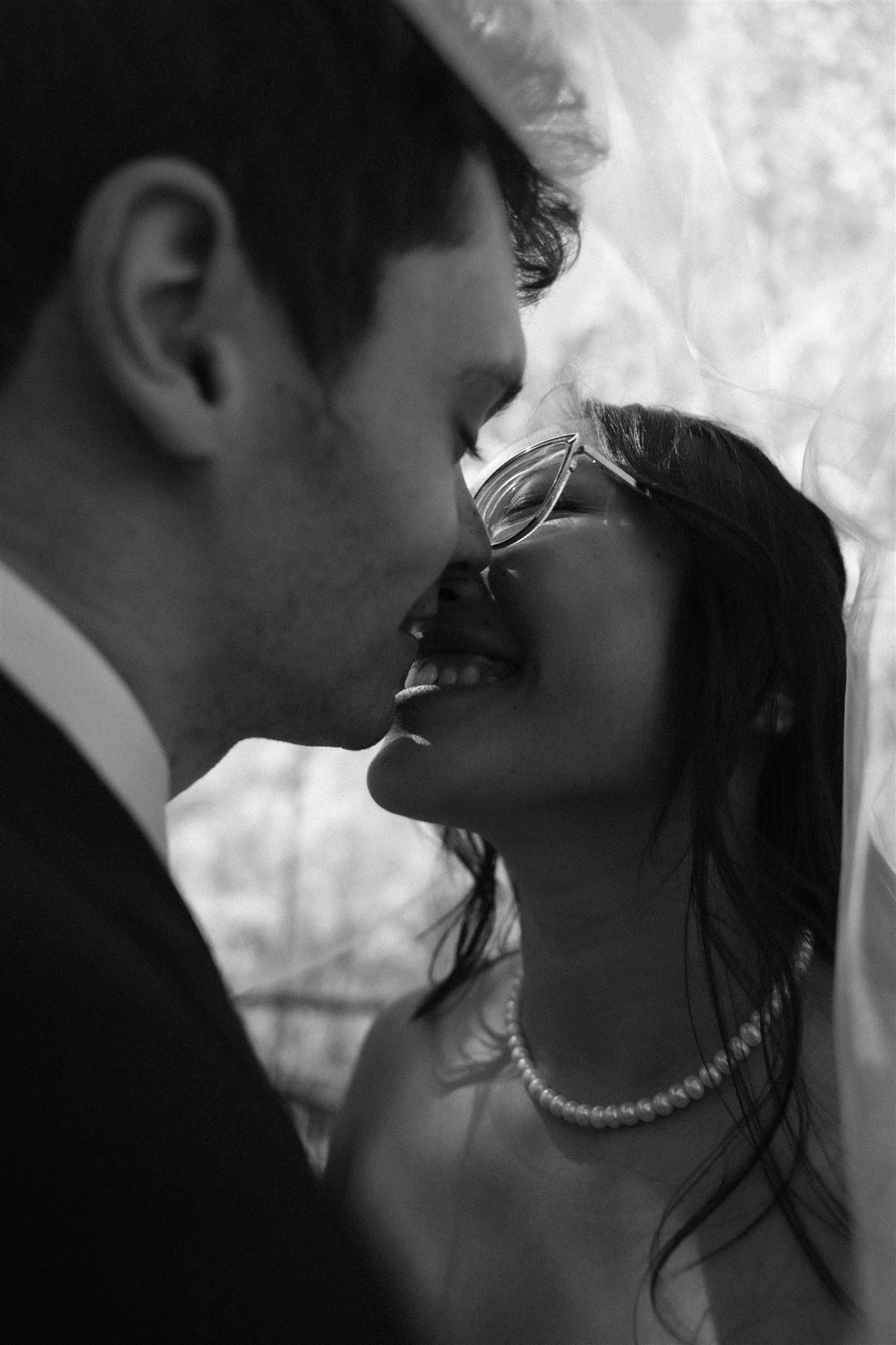 bride and groom under the veil smiling 