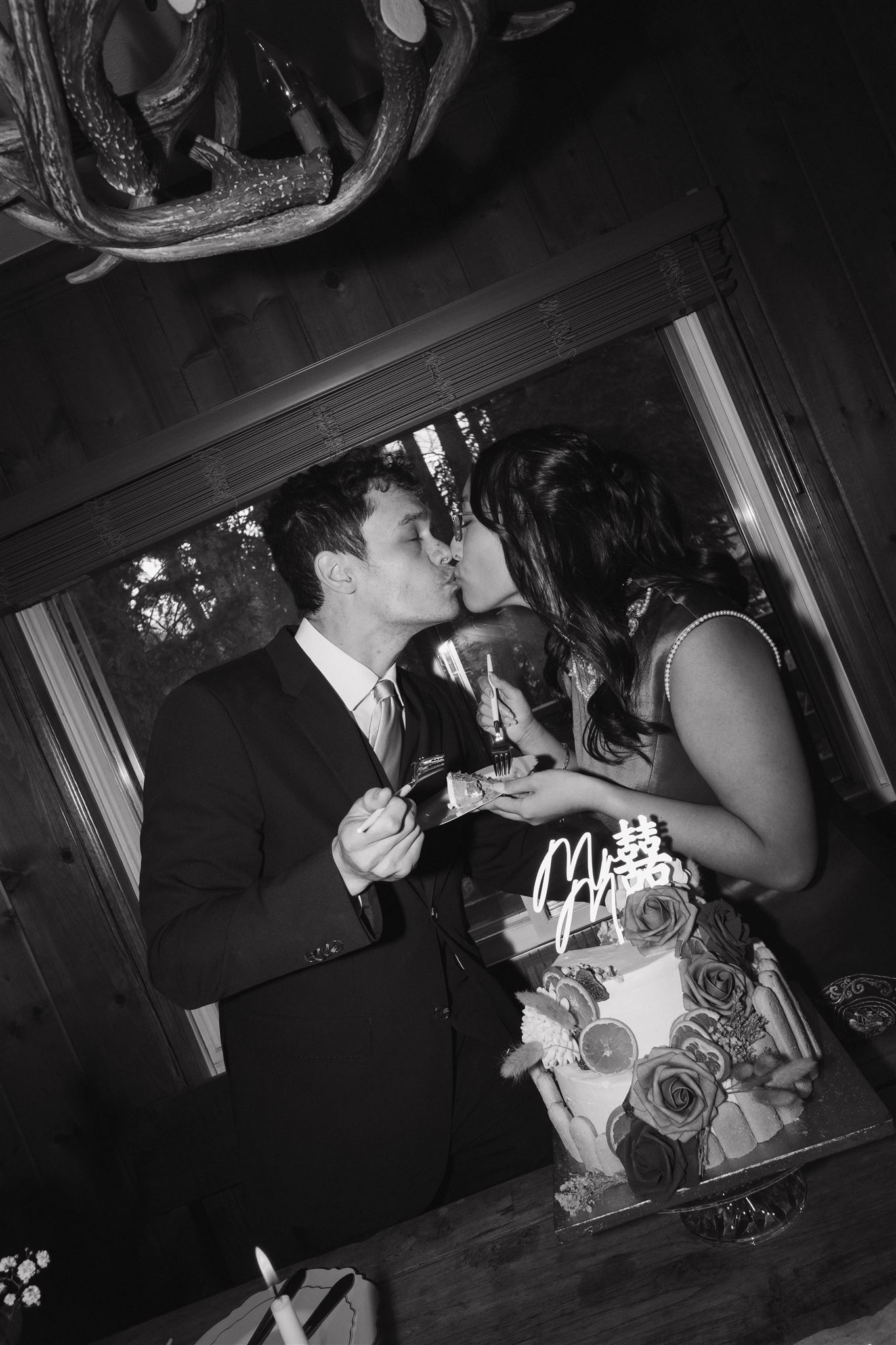 bride and groom kissing as they hold their cake 