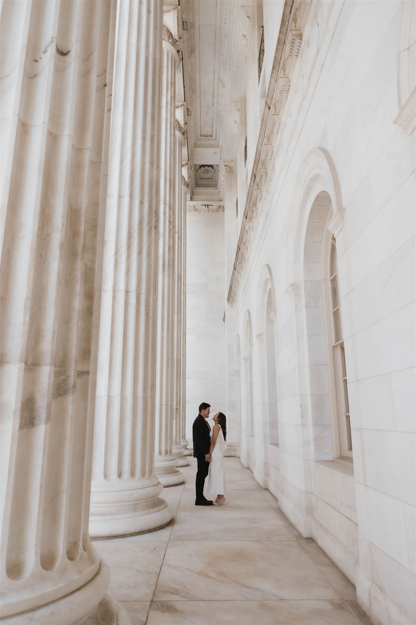 a couple holding hands by the grand pillars at the Denver courthouse 