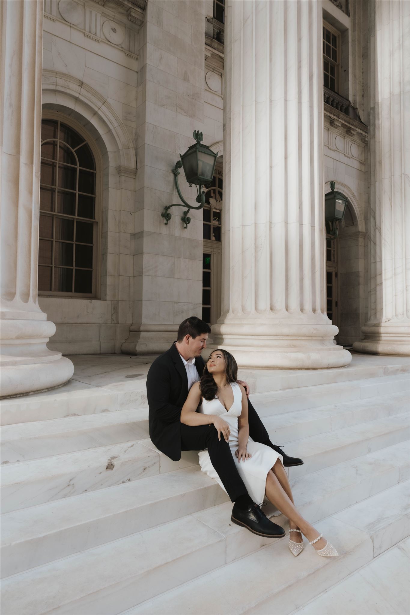 a newly engaged couple sitting together on the courthouse stairs 