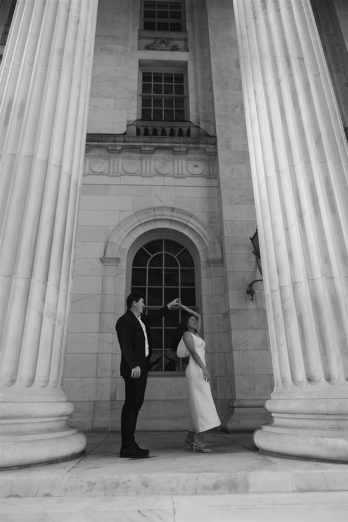 a man spinning a woman outside the Denver courthouse for Elegant Engagement Photos