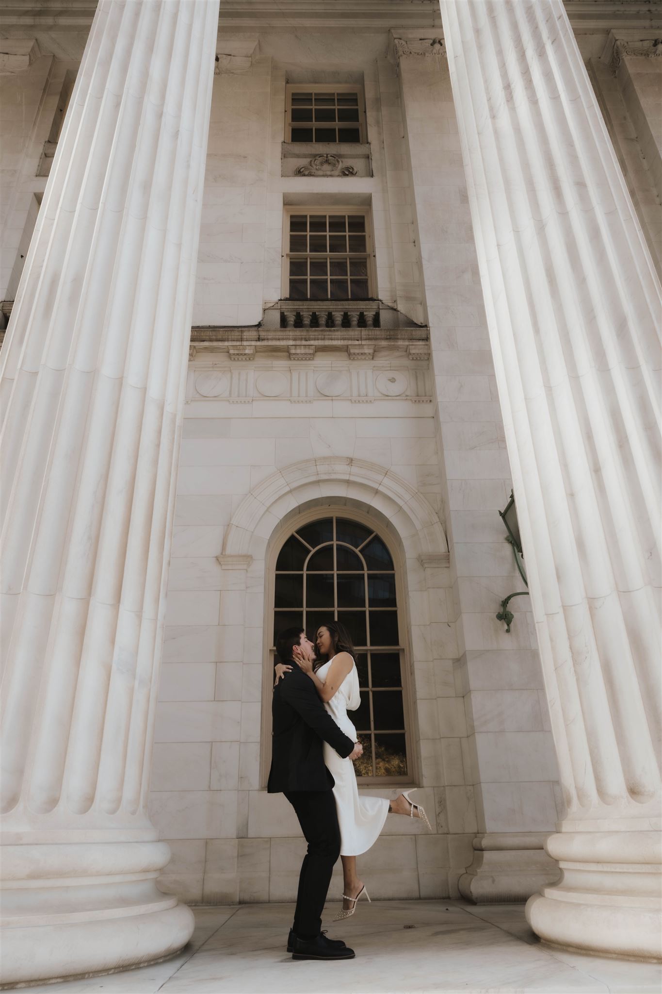 a man holding up a woman for their Elegant Engagement Photos at the courthouse 